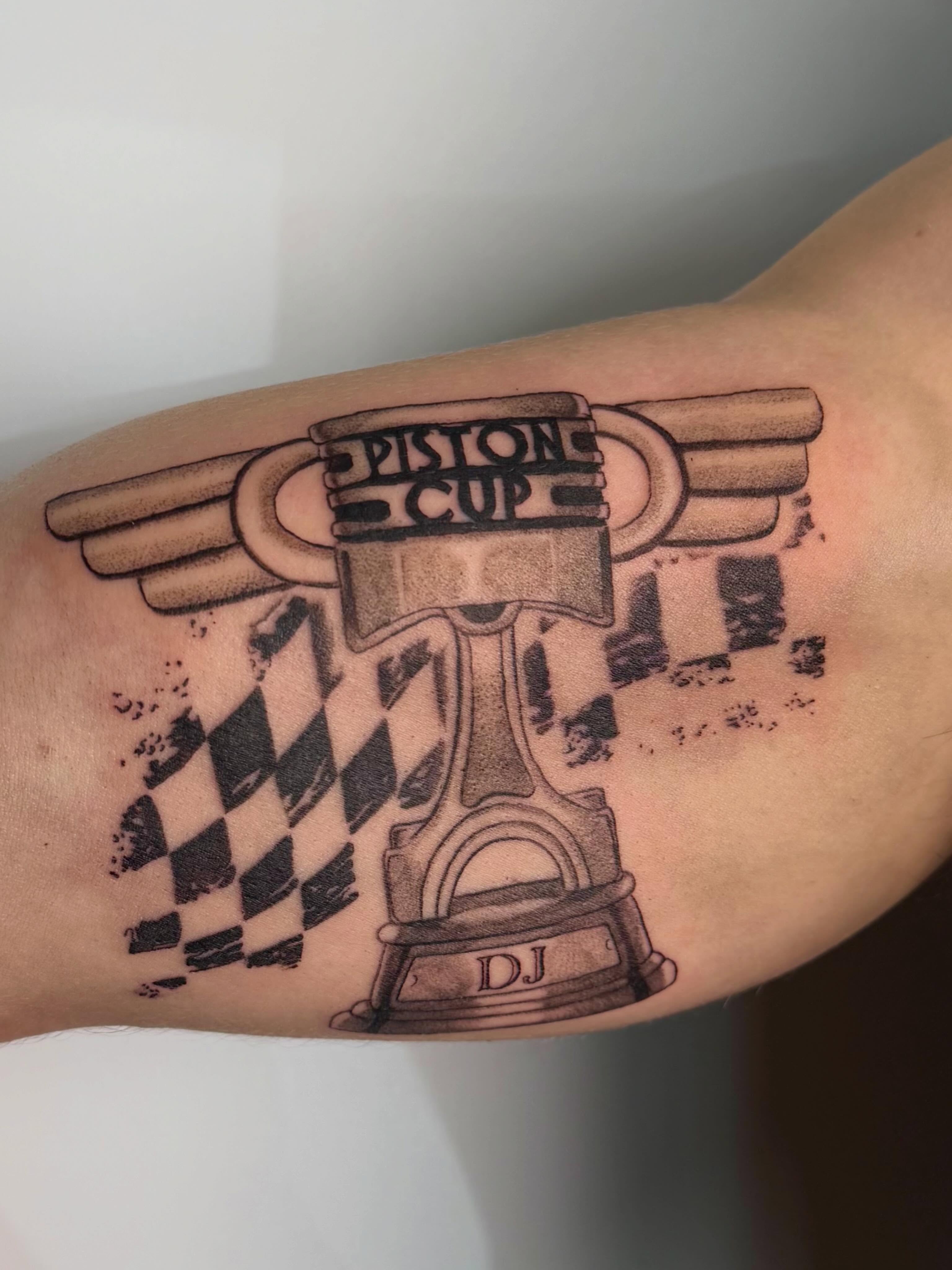 Piston cup black and grey tattoo on the forearm by Bailee