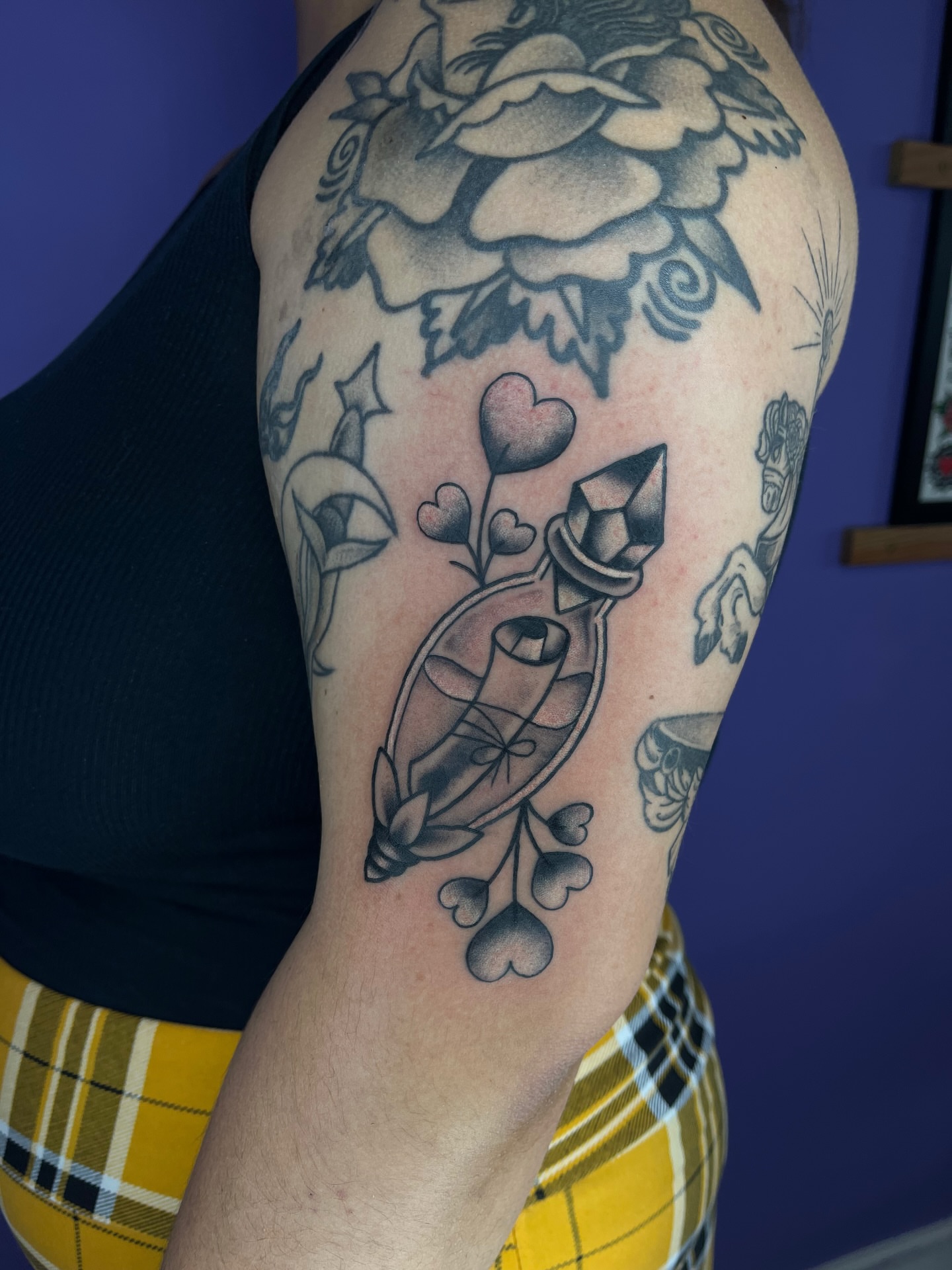 Glass bottle with hearts black and grey tattoo on the upper arm by Autumn**🍓NOW BOOKING