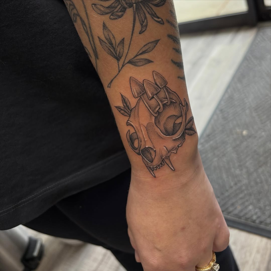 Skull with mushrooms black and grey tattoo on the forearm by Hailey Nicole
