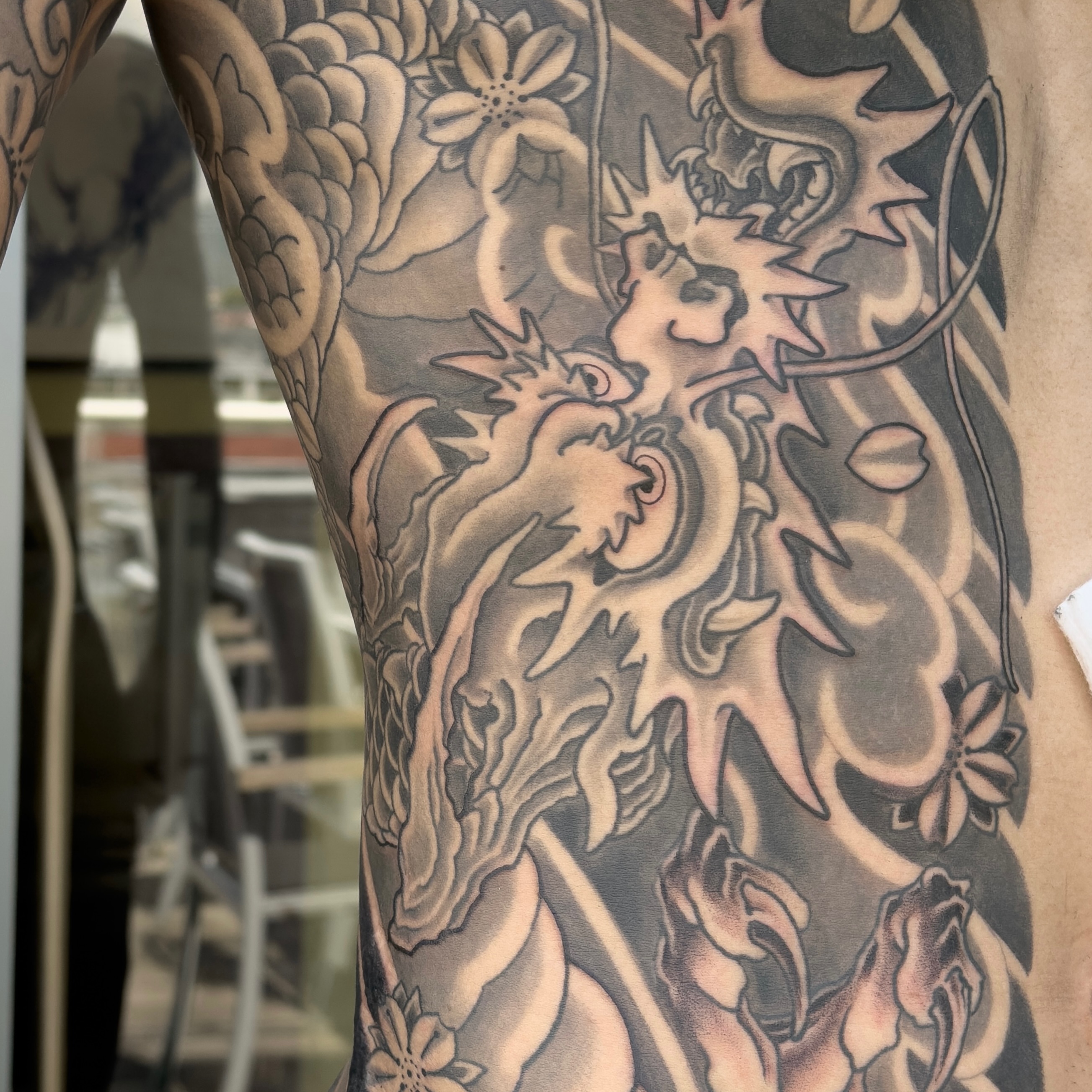 Lion and flowers black and grey tattoo on the thigh by James Bird, Vancouver, British Columbia