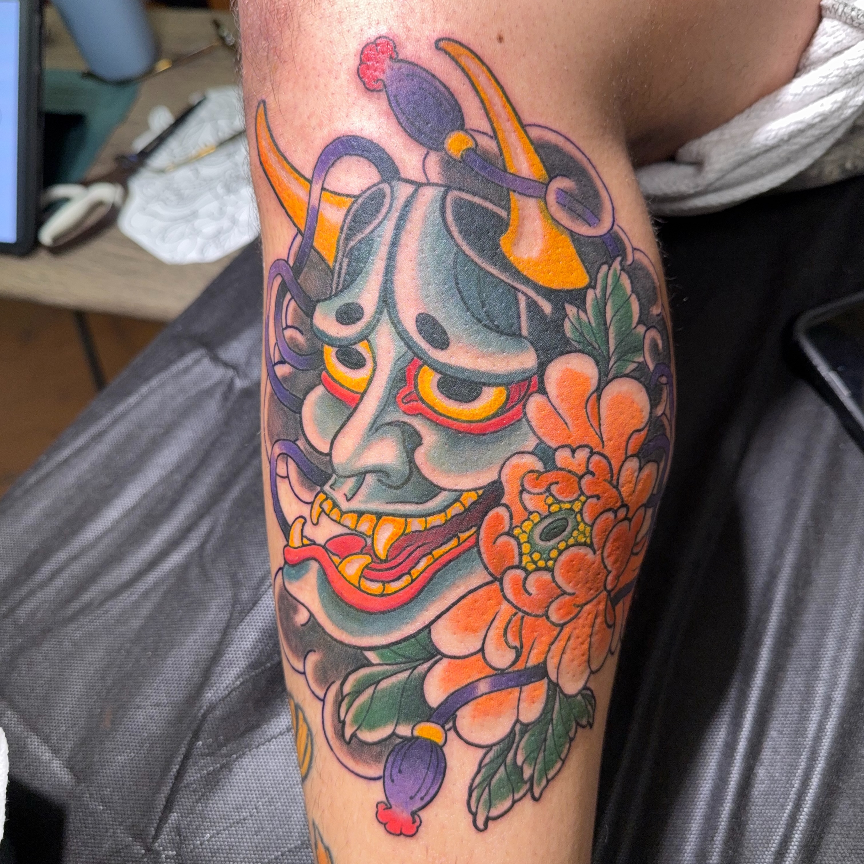 Mask and flowers American traditional tattoo on the forearm by James Bird, Vancouver, British Columbia