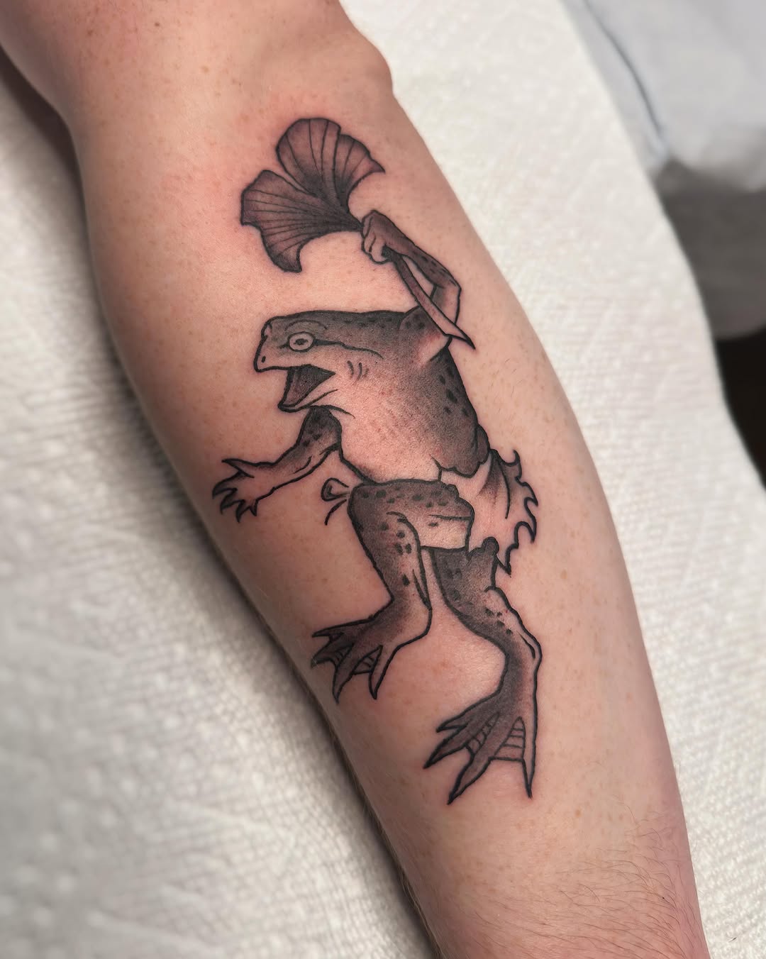 Frog with hat black and grey tattoo on the forearm by Craig Ryans