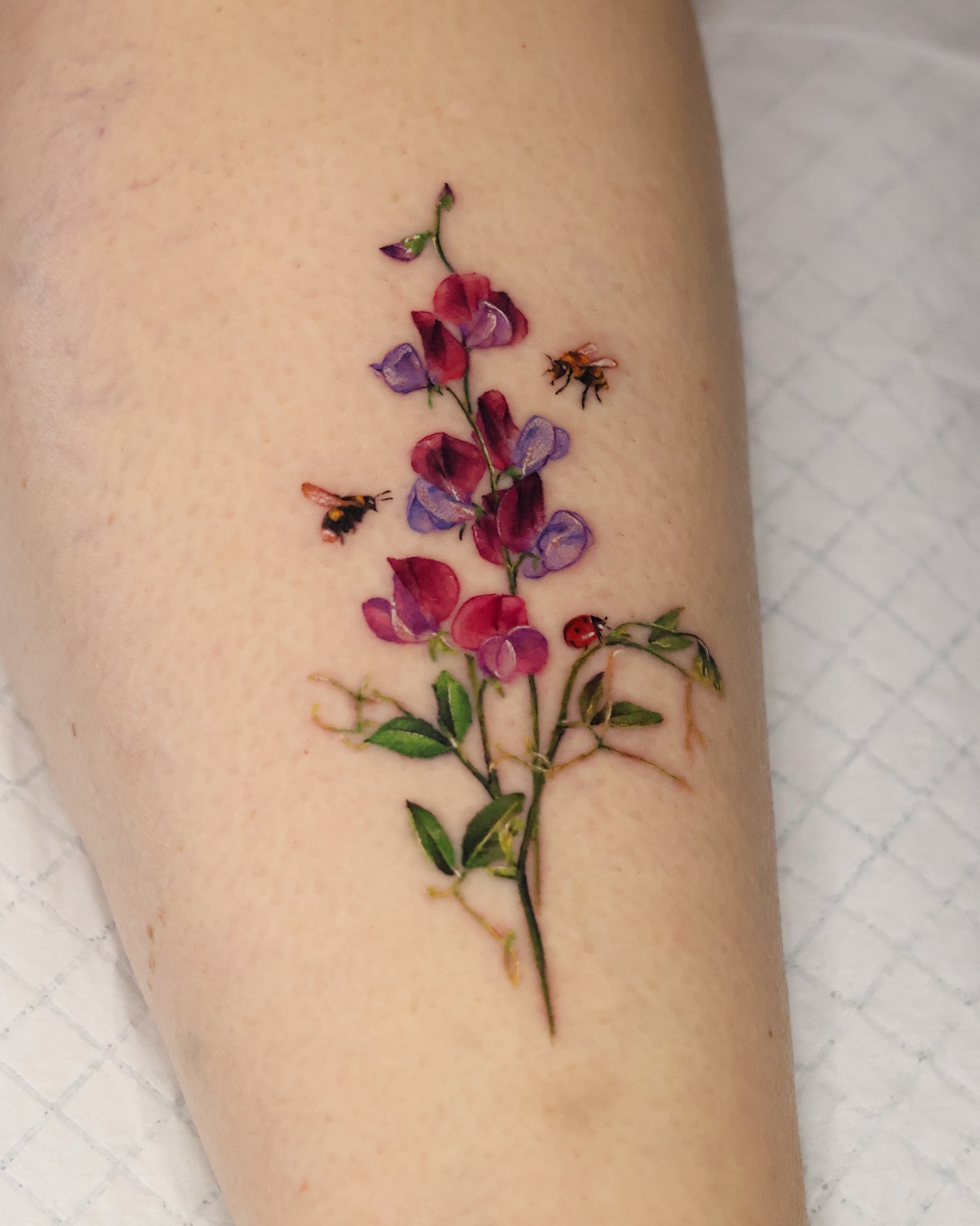 Sweet pea flowers and bees realism tattoo on the forearm by 𝒀𝒖𝒏𝒎𝒊 𝑷𝒂𝒓𝒌