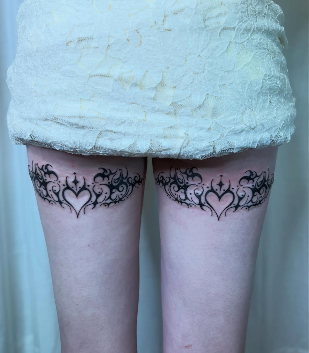 Hearts and flourishes tribal tattoo on the thigh by Skitty Tattoo Artist