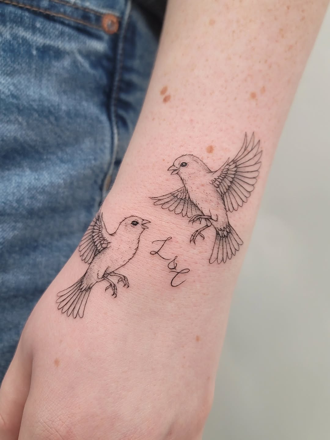 Two birds and script lettering fine line tattoo on the forearm by Las Vegas Fine Line Tattoos