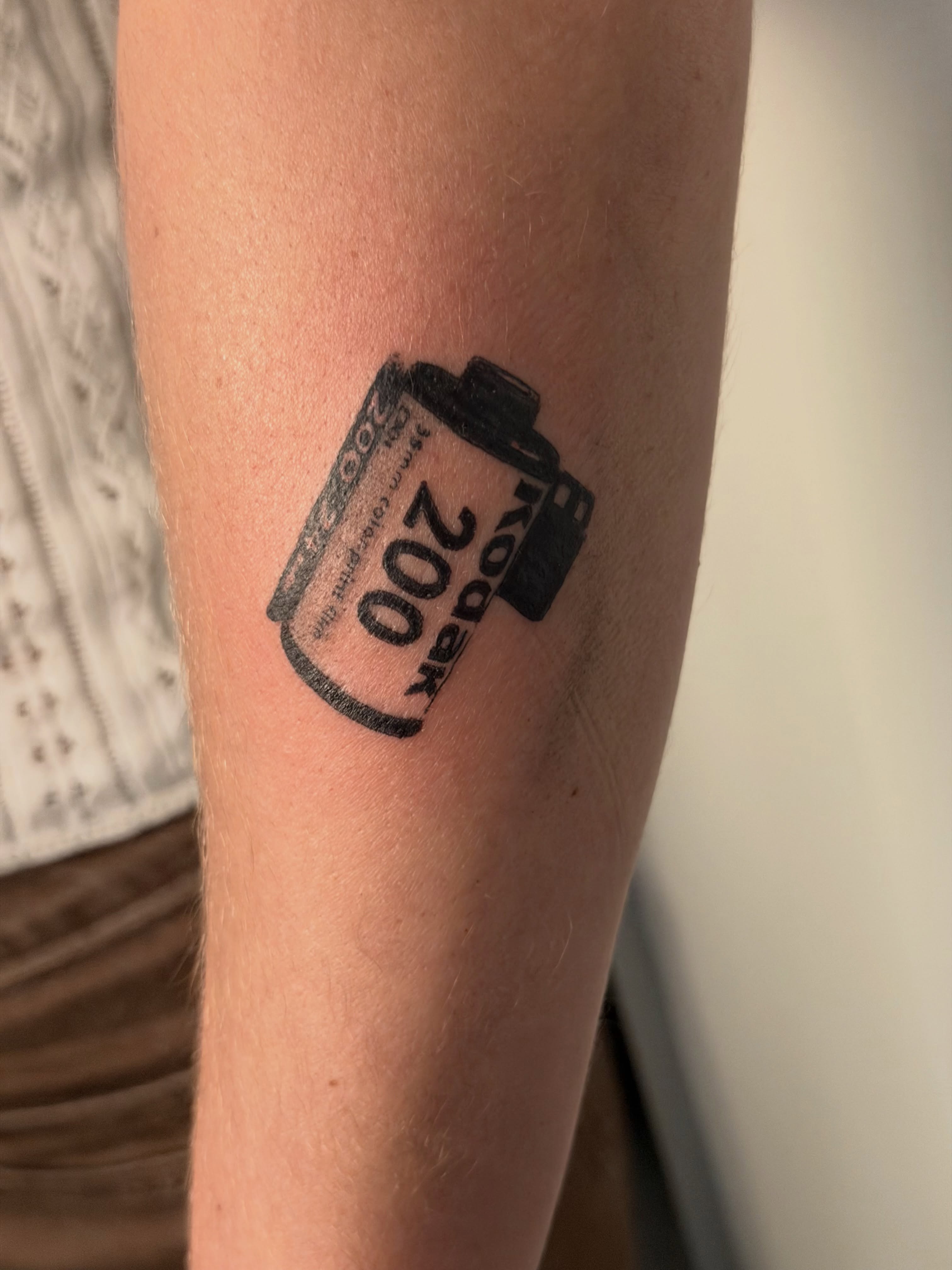 Film roll black and grey tattoo on the forearm by Alaska