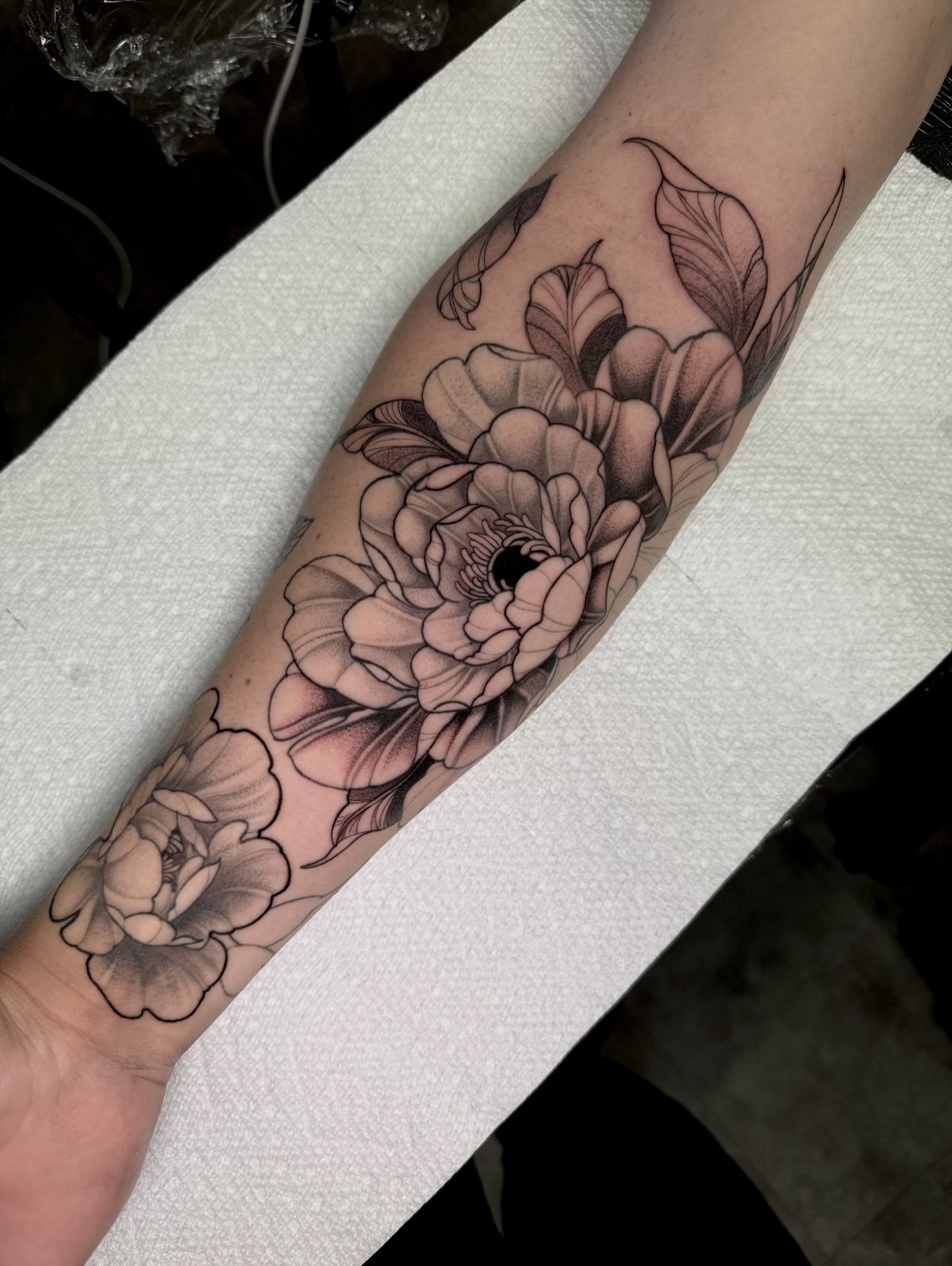 Peony flowers black and grey tattoo on the forearm by Tattoo Artist Vanessa