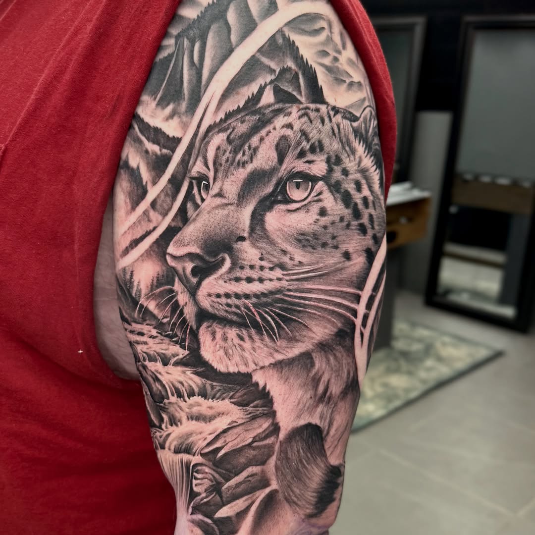 Snow leopard realism tattoo on the upper arm by Indiana Tattoo Artist
