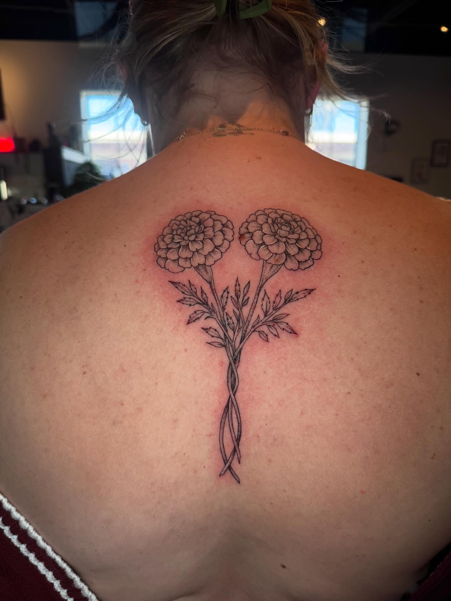Marigolds black and grey tattoo on the back by Gabrielle Mack