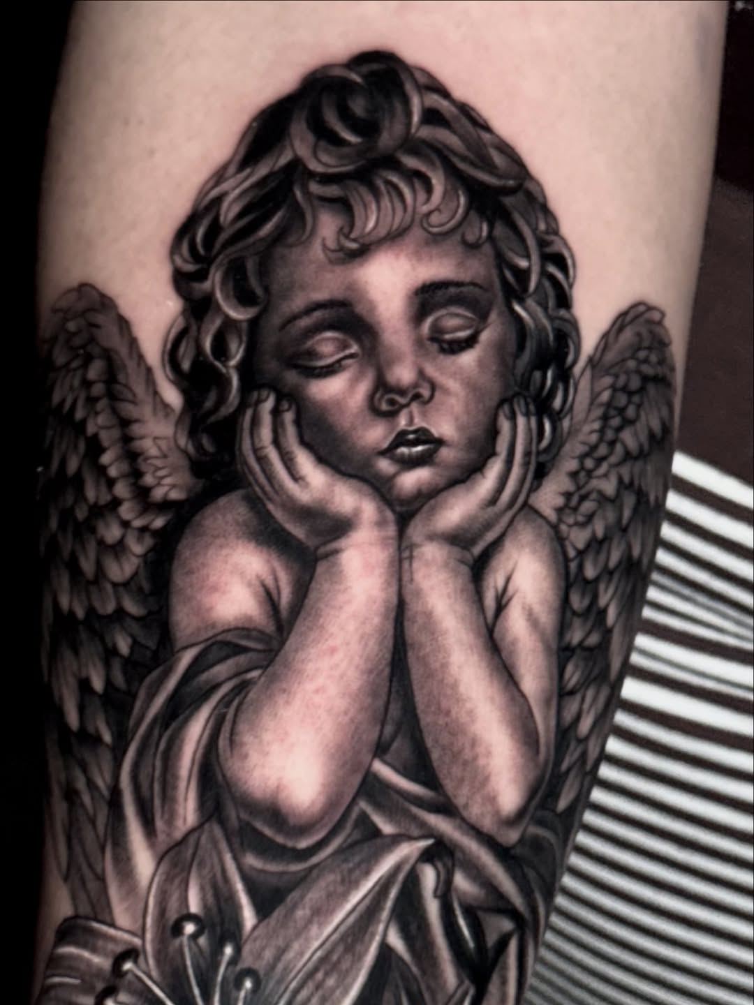 Cherub with lilies realism tattoo on the forearm by Chris galvis, Charlotte, North Carolina