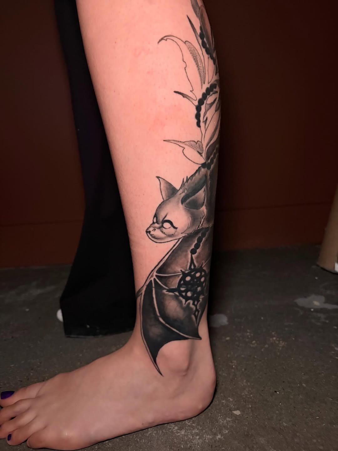 Bat with floral elements ornamental tattoo on the calf by Kenzie Mecham-Cunningham
