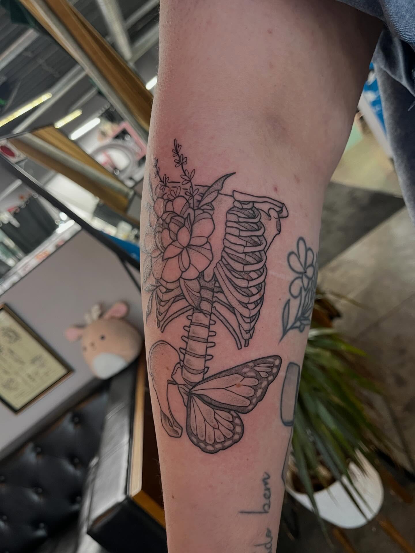 Ribcage with flowers and butterfly black and grey tattoo on the forearm by bunny, Minneapolis, Minnesota