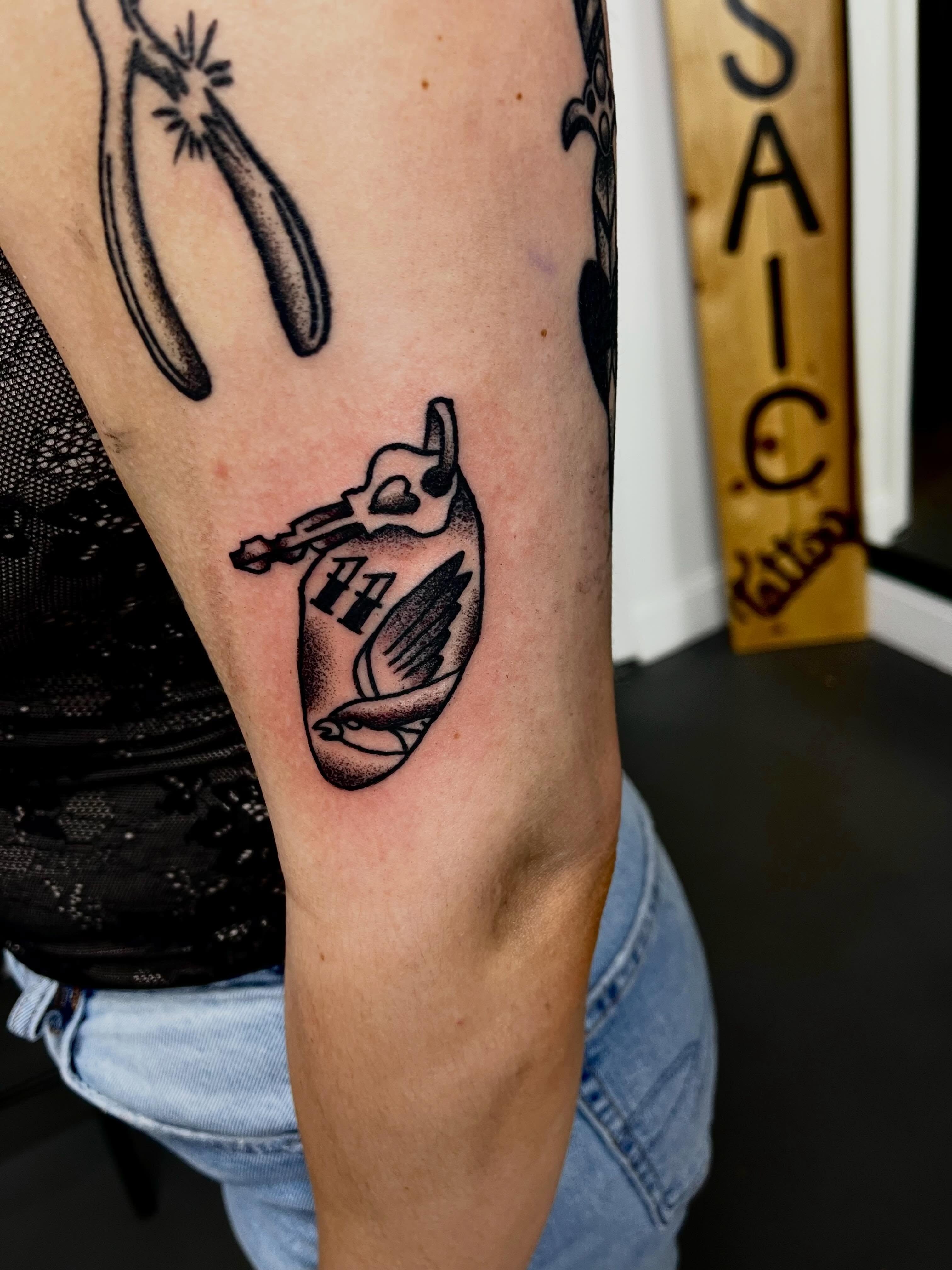Bird with wings black and grey tattoo on the forearm by Mason McCubbin