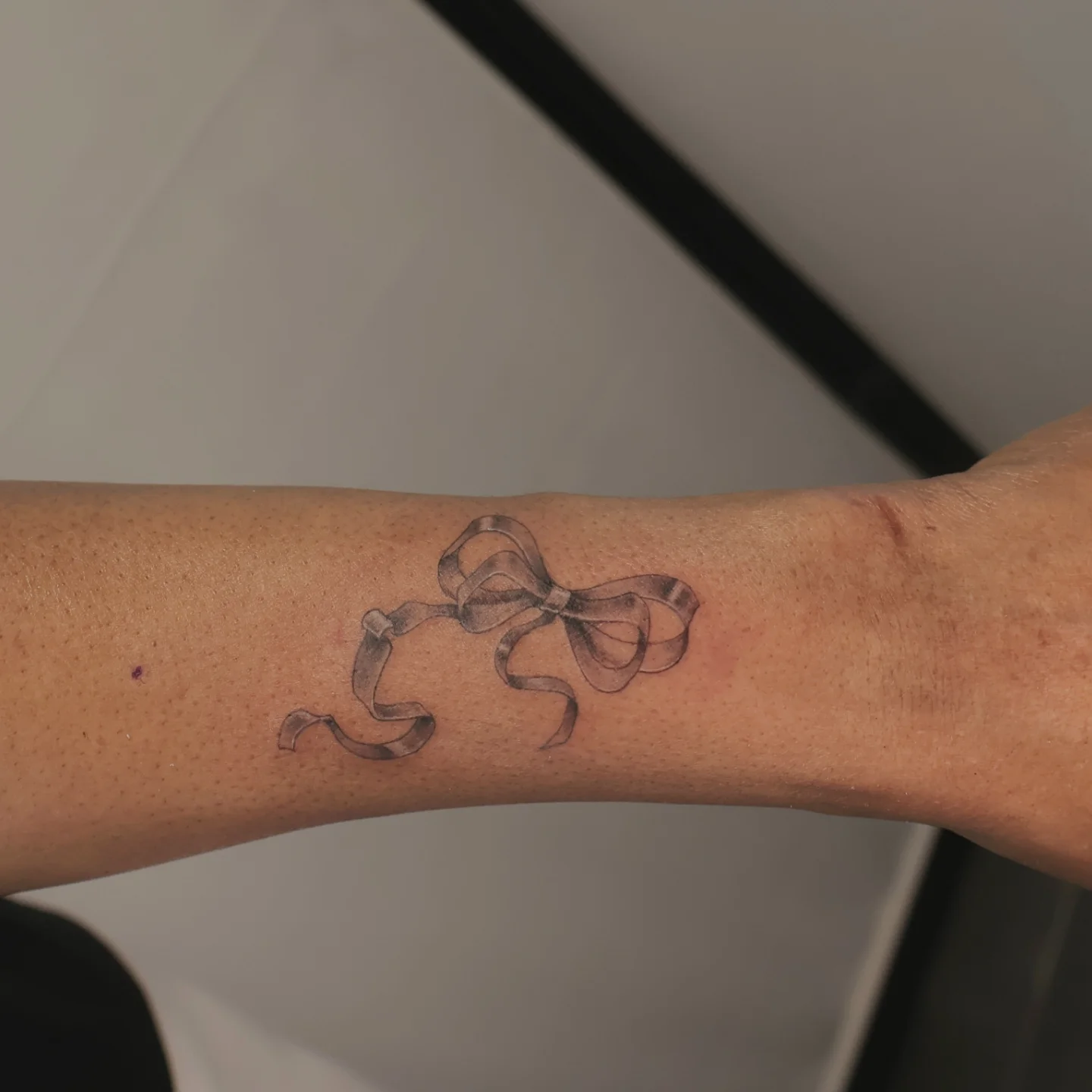 Bow black and grey tattoo on the forearm by Joc