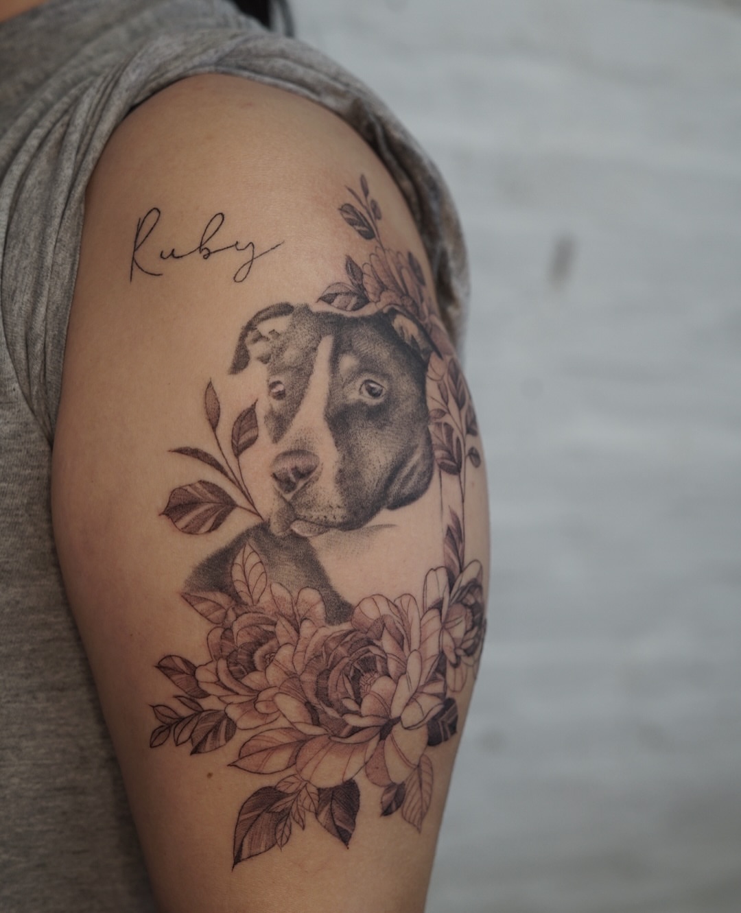 Dog with floral wreath realism tattoo on the shoulder by Josh Infante