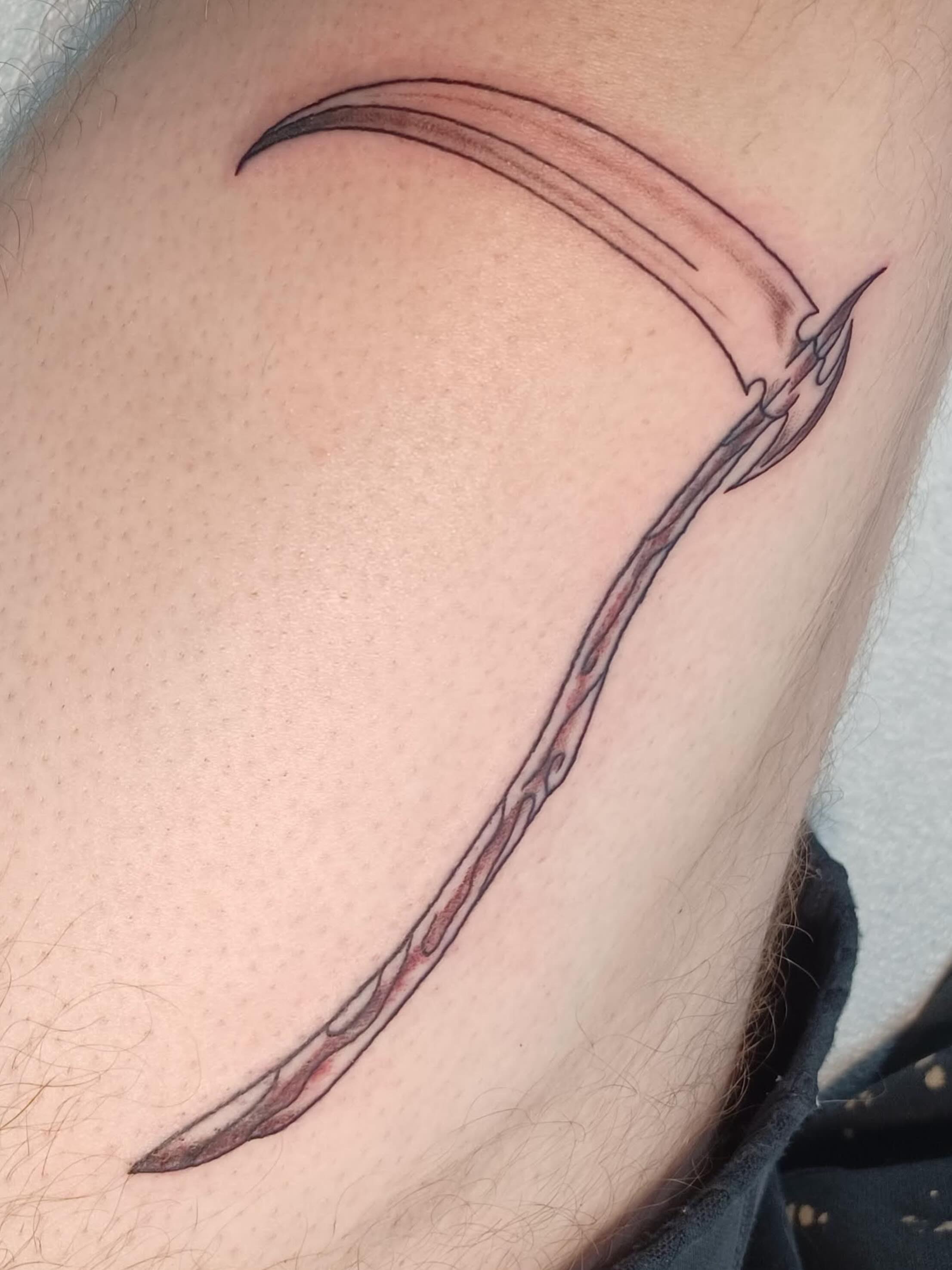 Scythe black and grey tattoo on the upper arm by Abi