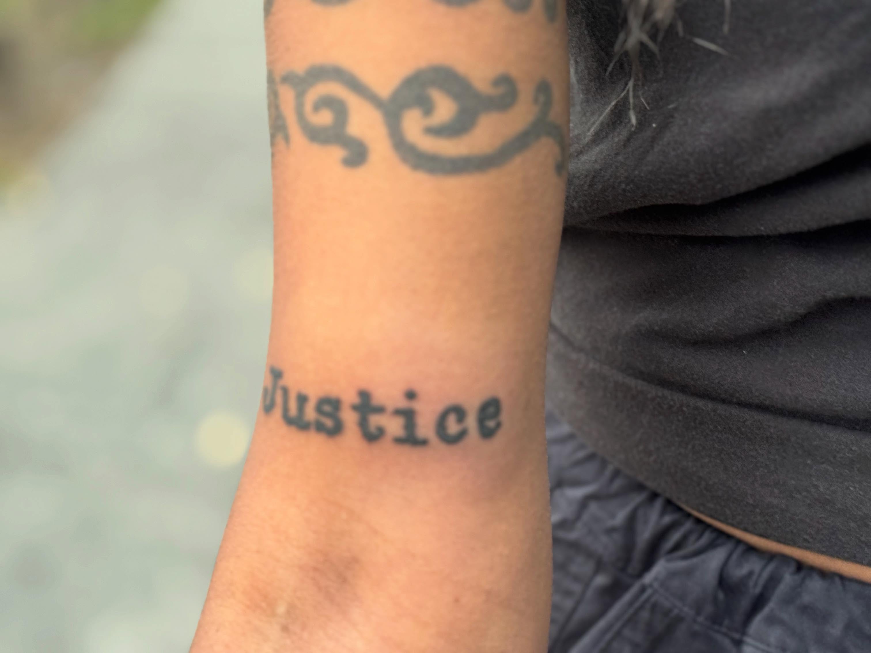 Justice black and grey tattoo on the forearm by Gabe