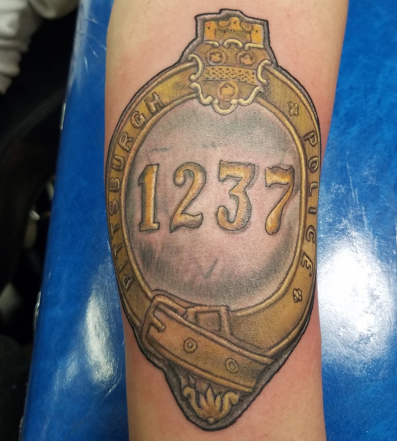 Police badge realism tattoo on the forearm by Oz Dillinger