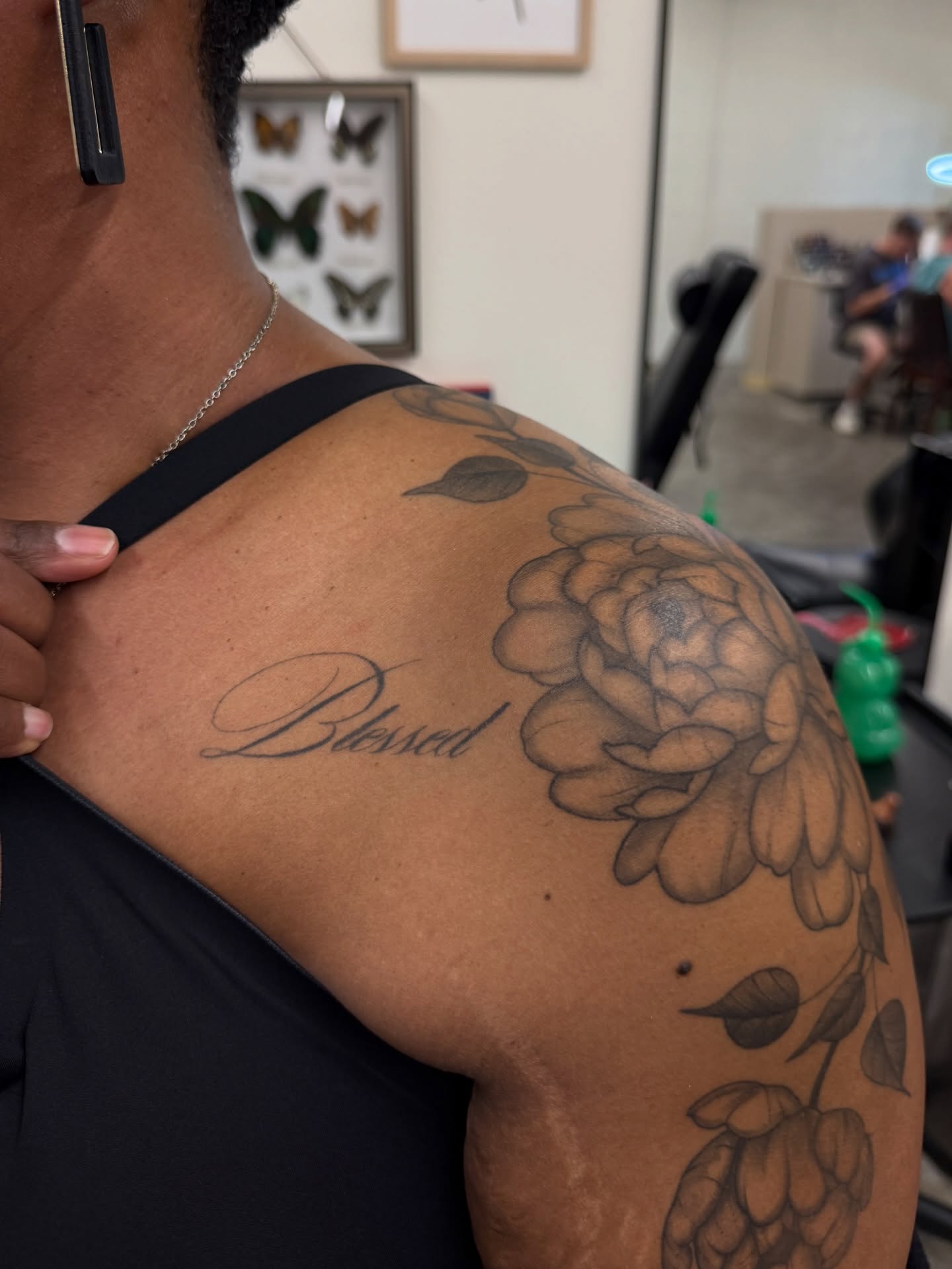 Flower and script black and grey tattoo on the shoulder by Kiana Hope