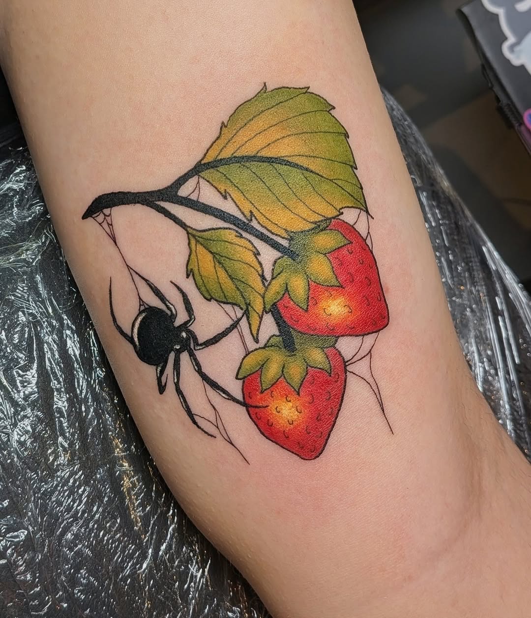 Spider and strawberries watercolor tattoo on the forearm by Damon 🥀