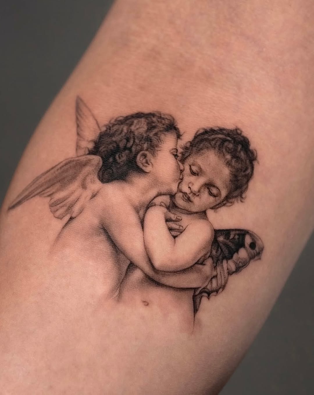 Two cherubs with a moth realism tattoo on the forearm by Valery Cardona