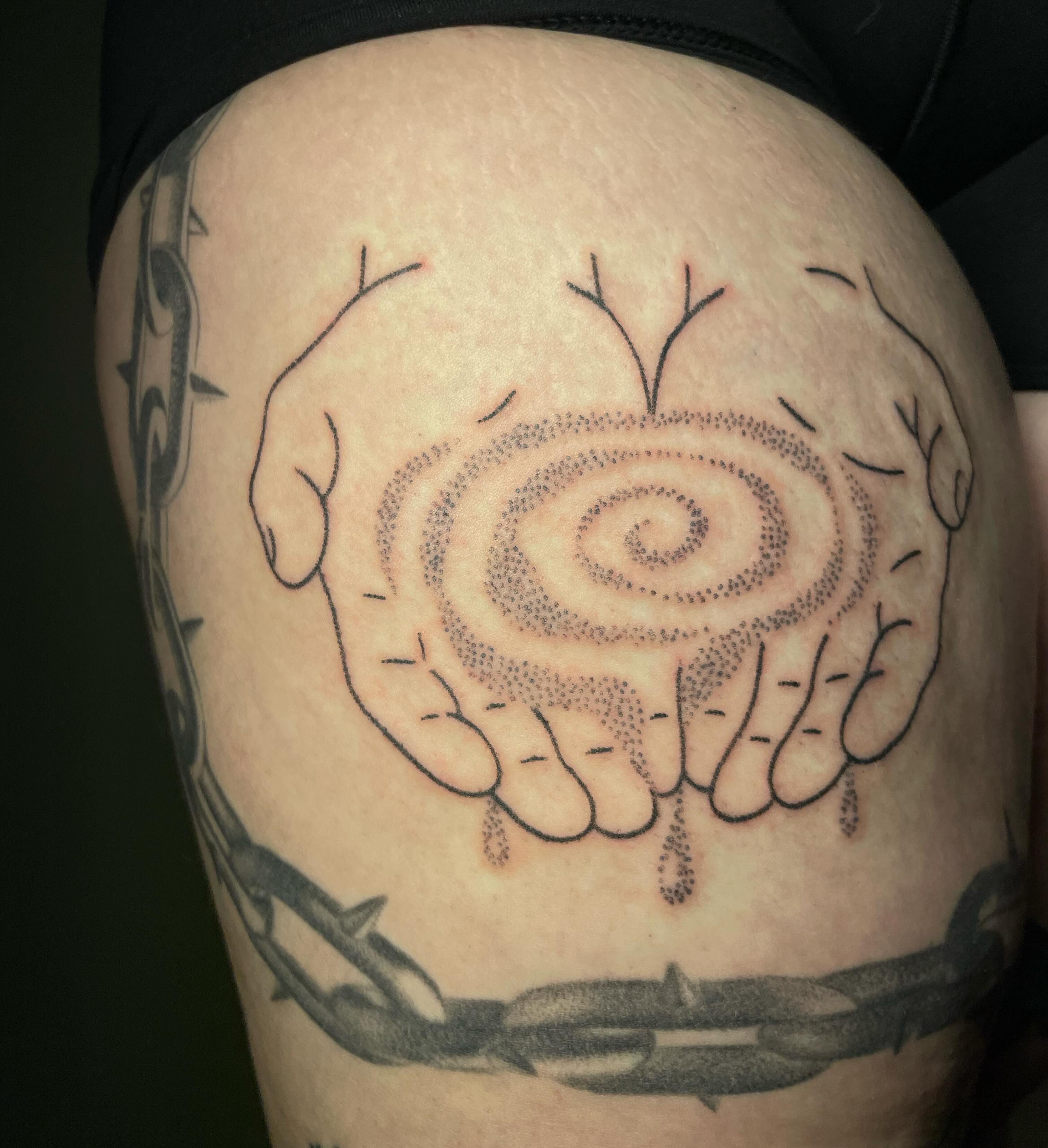 Hands holding spiral dotwork tattoo on the thigh by Quin