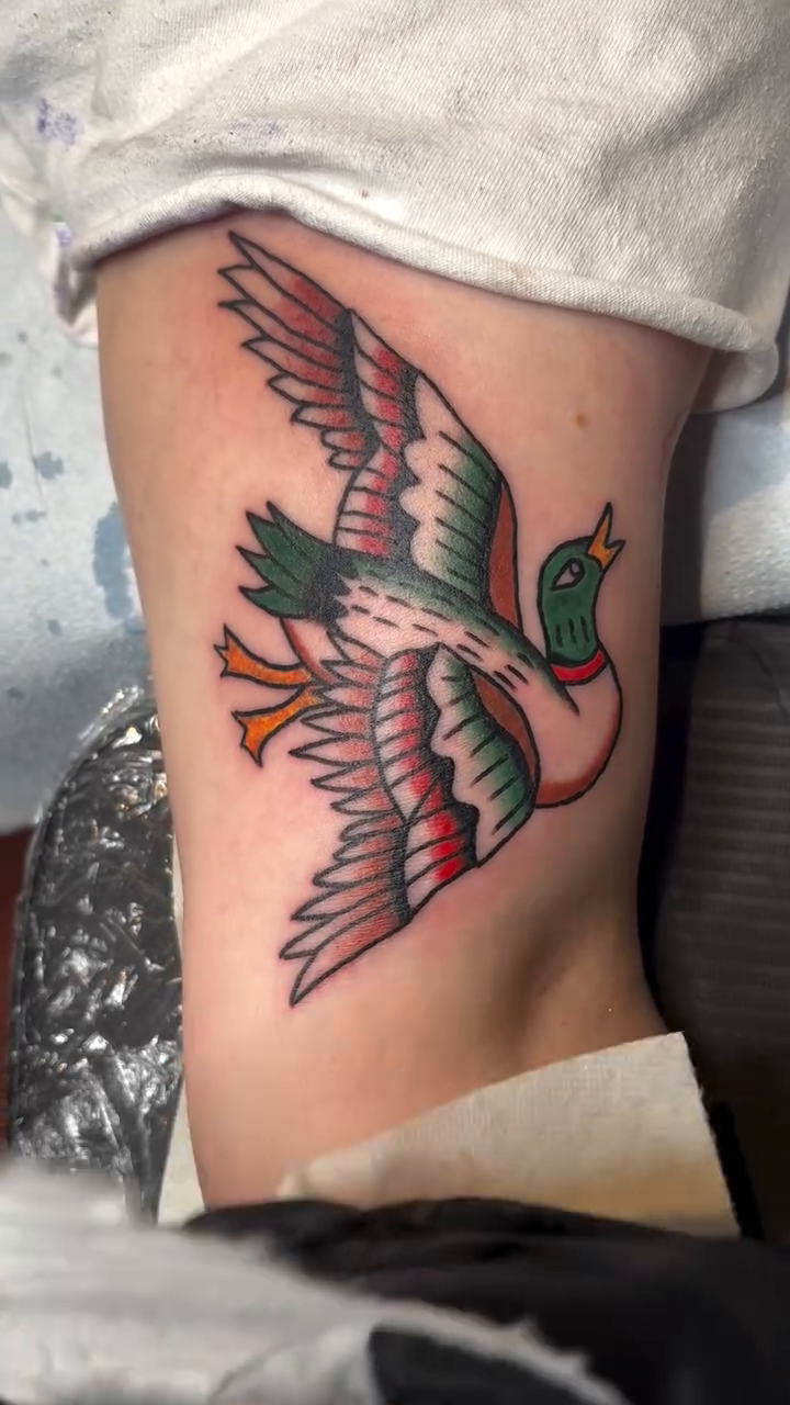 Flying duck American traditional tattoo on the upper arm by ellie