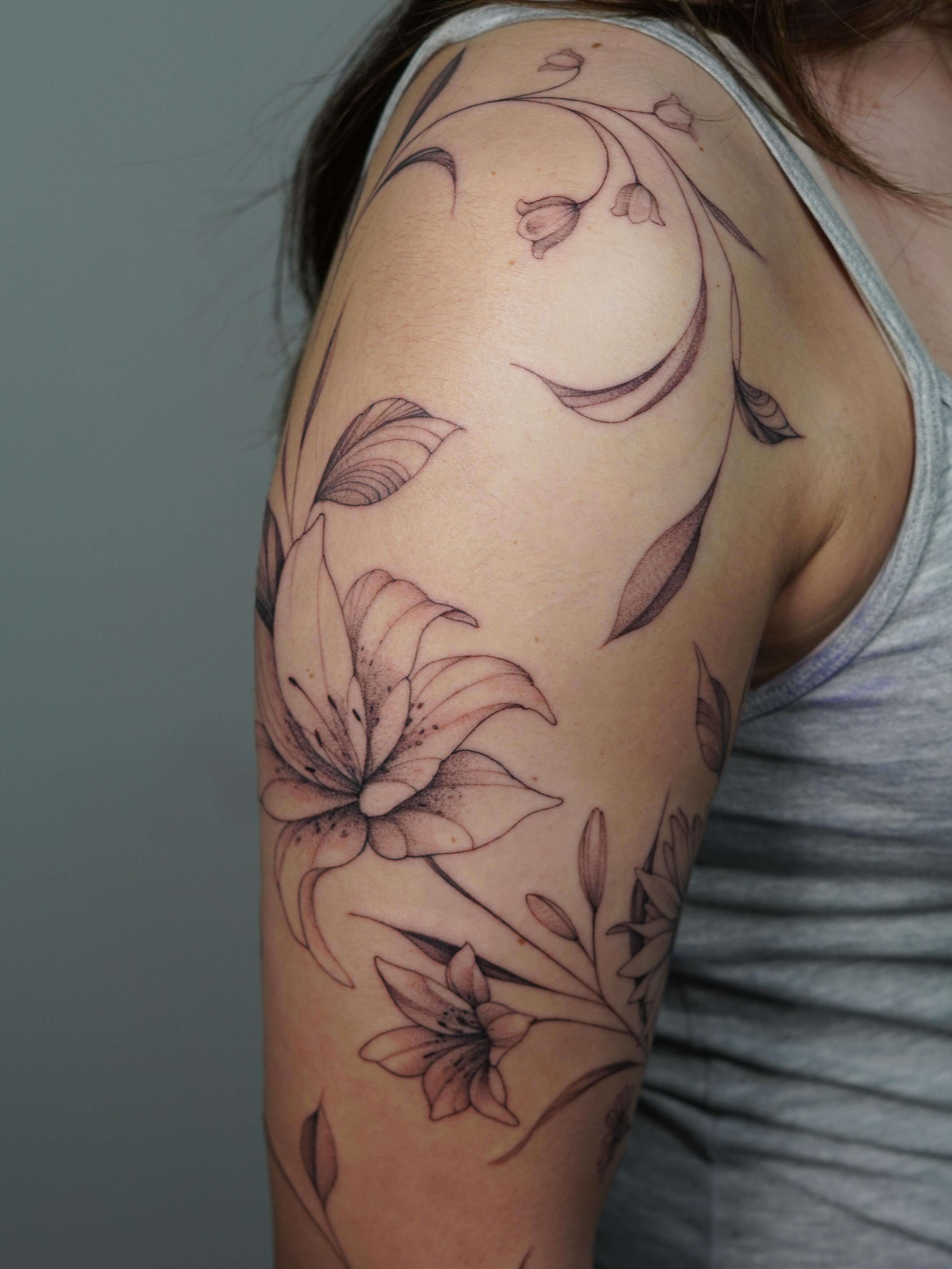 Lily flowers black and grey tattoo on the shoulder by Danae Andino