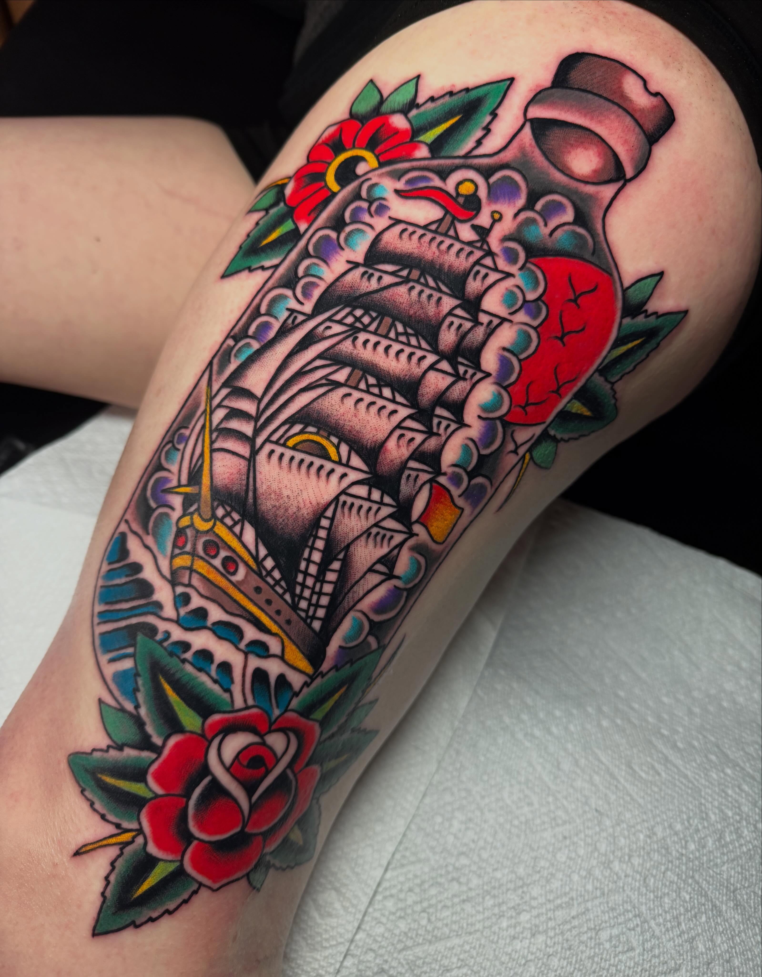 Ship and roses American traditional tattoo on the thigh by Chris Dufresne