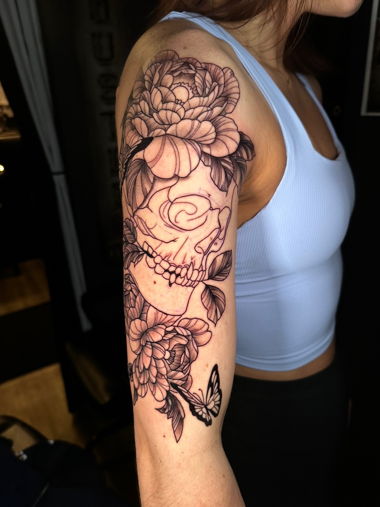 Skull and flowers realism tattoo on the forearm by Beau Zeis