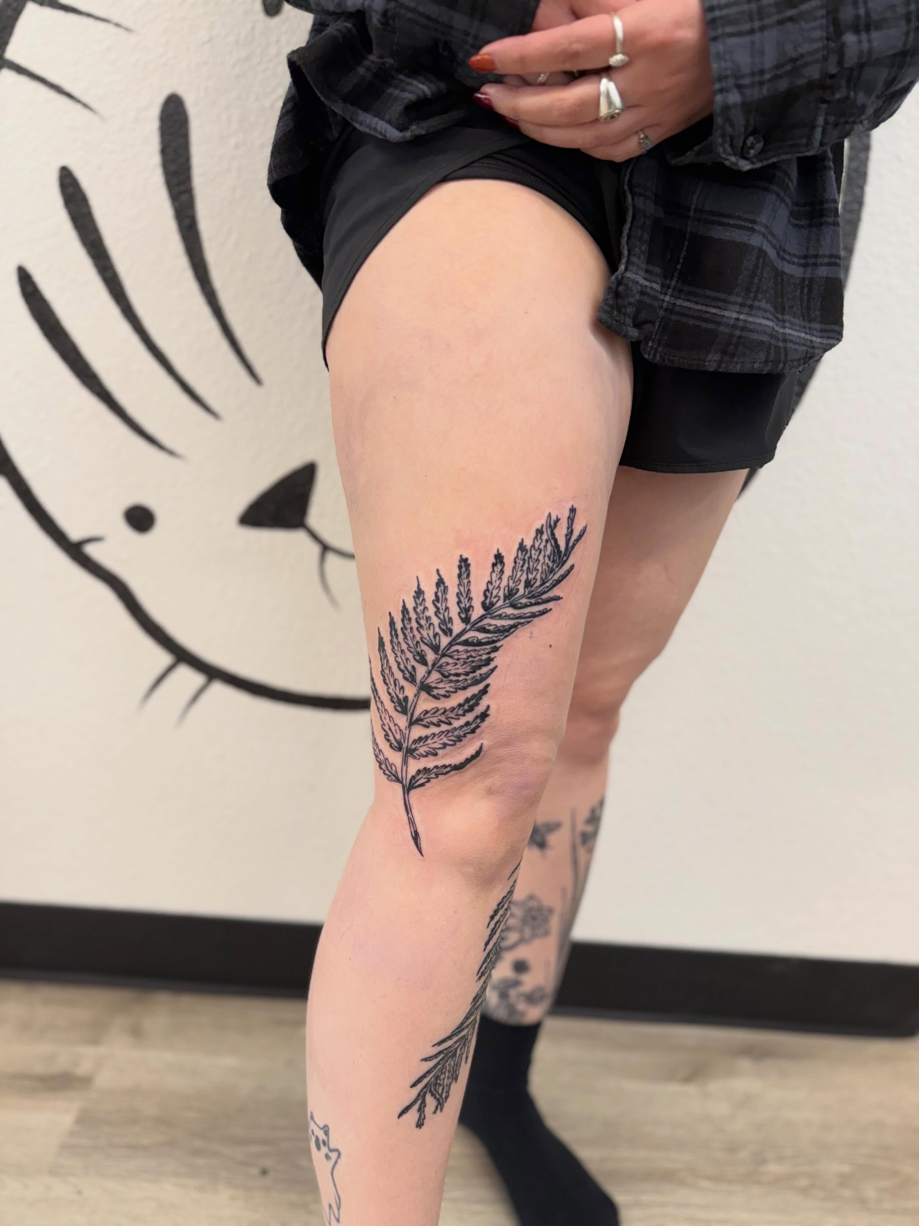 Fern leaf black and grey tattoo on the thigh by Peggy