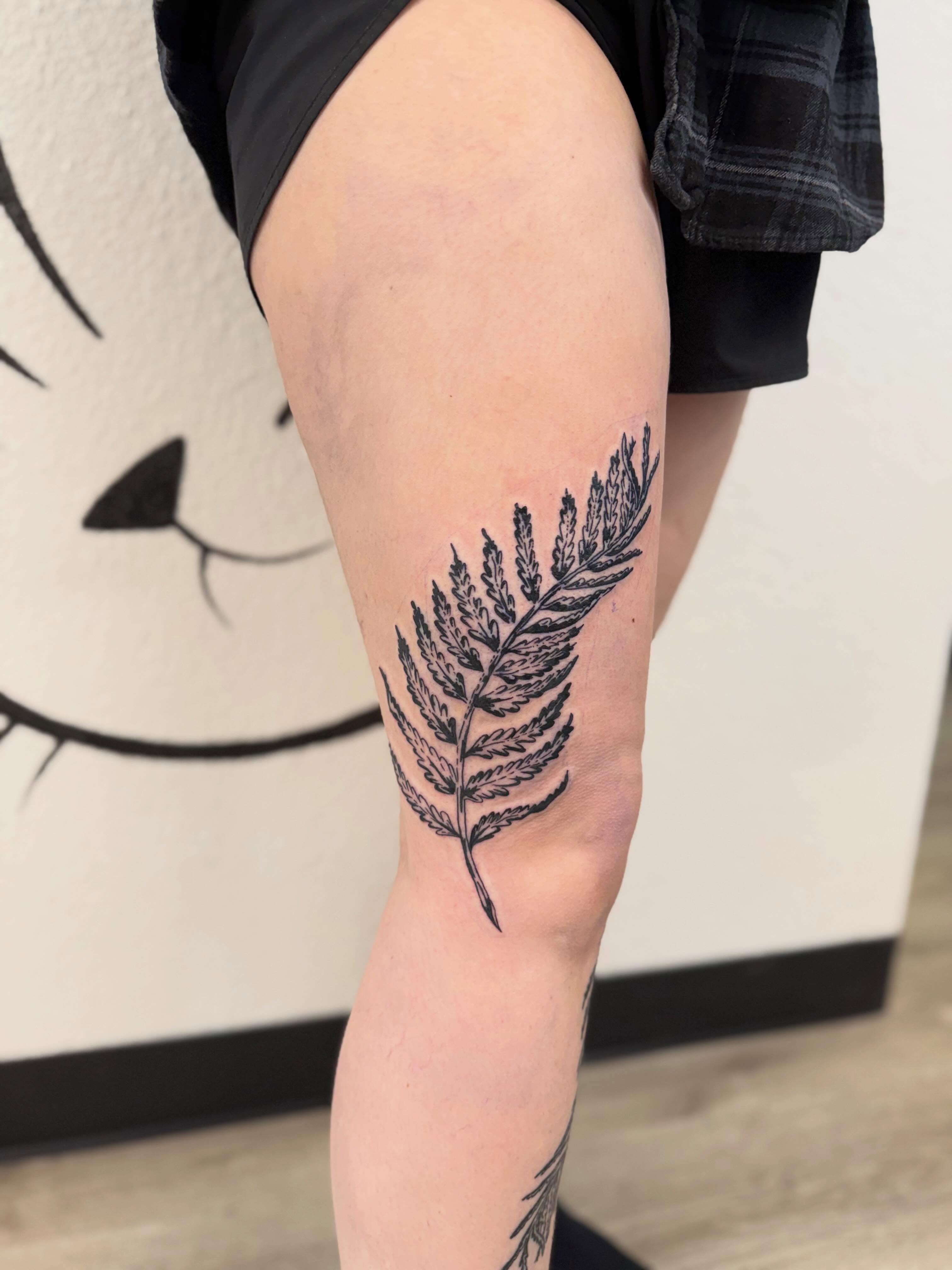 Fern leaf black and grey tattoo on the thigh by Peggy
