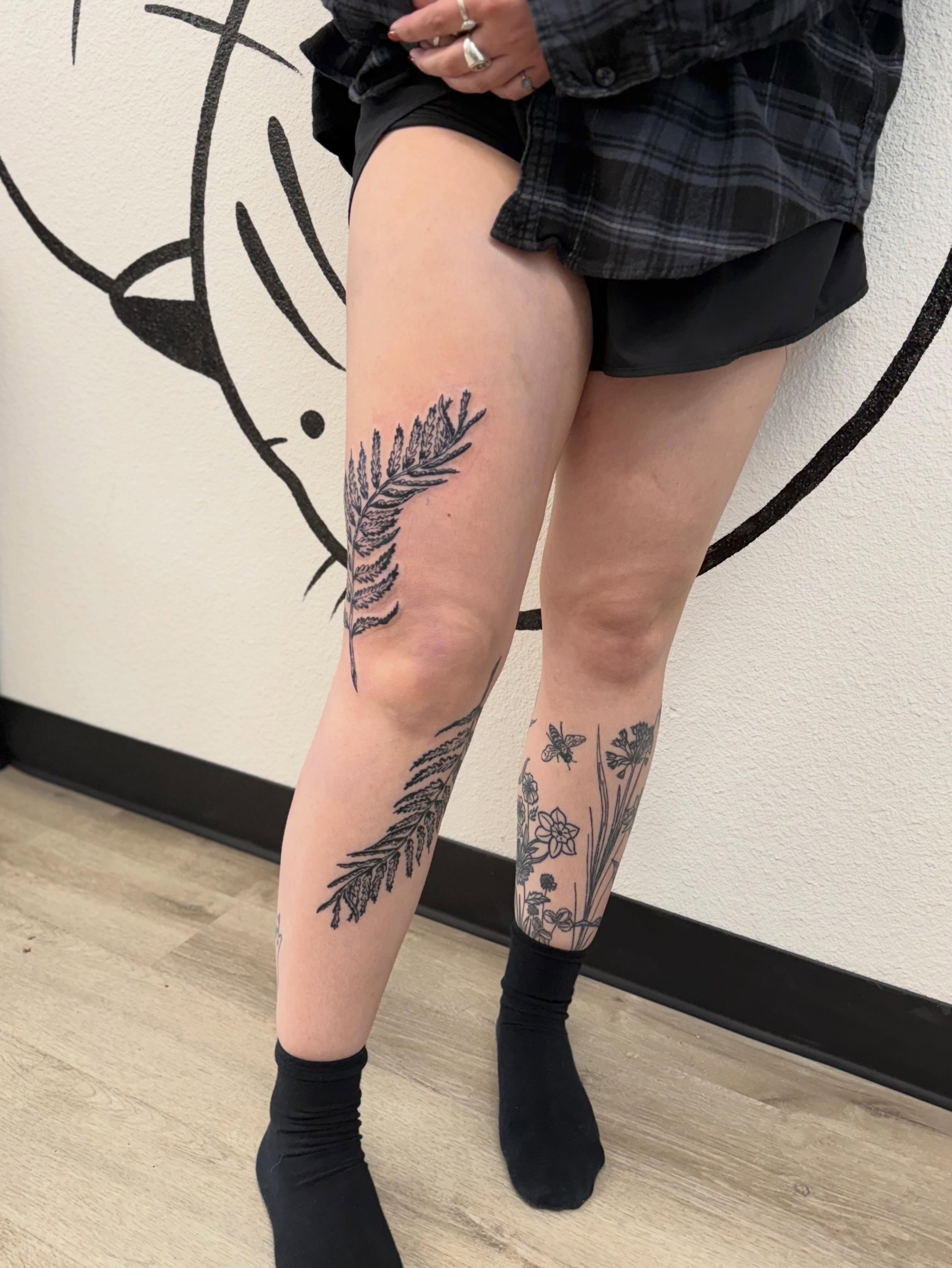 Feather and flowers black and grey tattoo on the thigh by Peggy