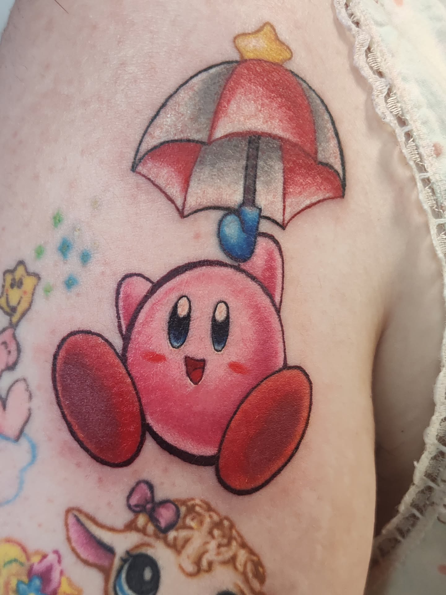 Kirby with umbrella anime tattoo on the upper arm by Mercury