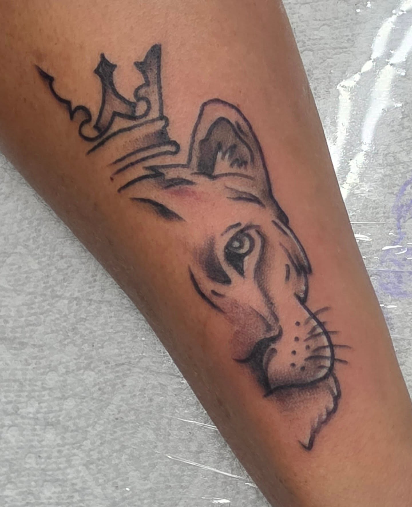 Lion crown realism tattoo on the forearm by Moe