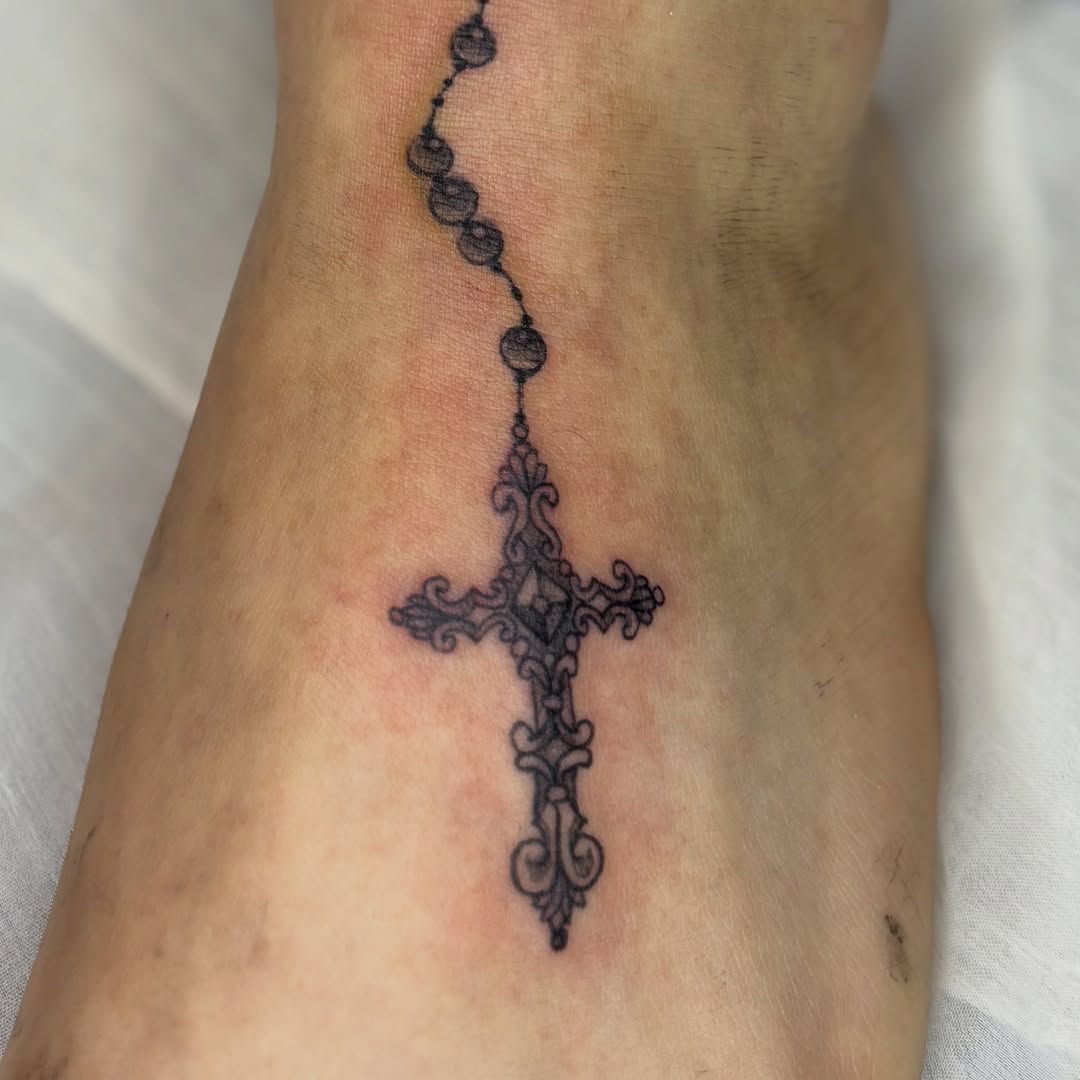 Cross black and grey tattoo on the foot by Weho Tattoo Artist Lupe