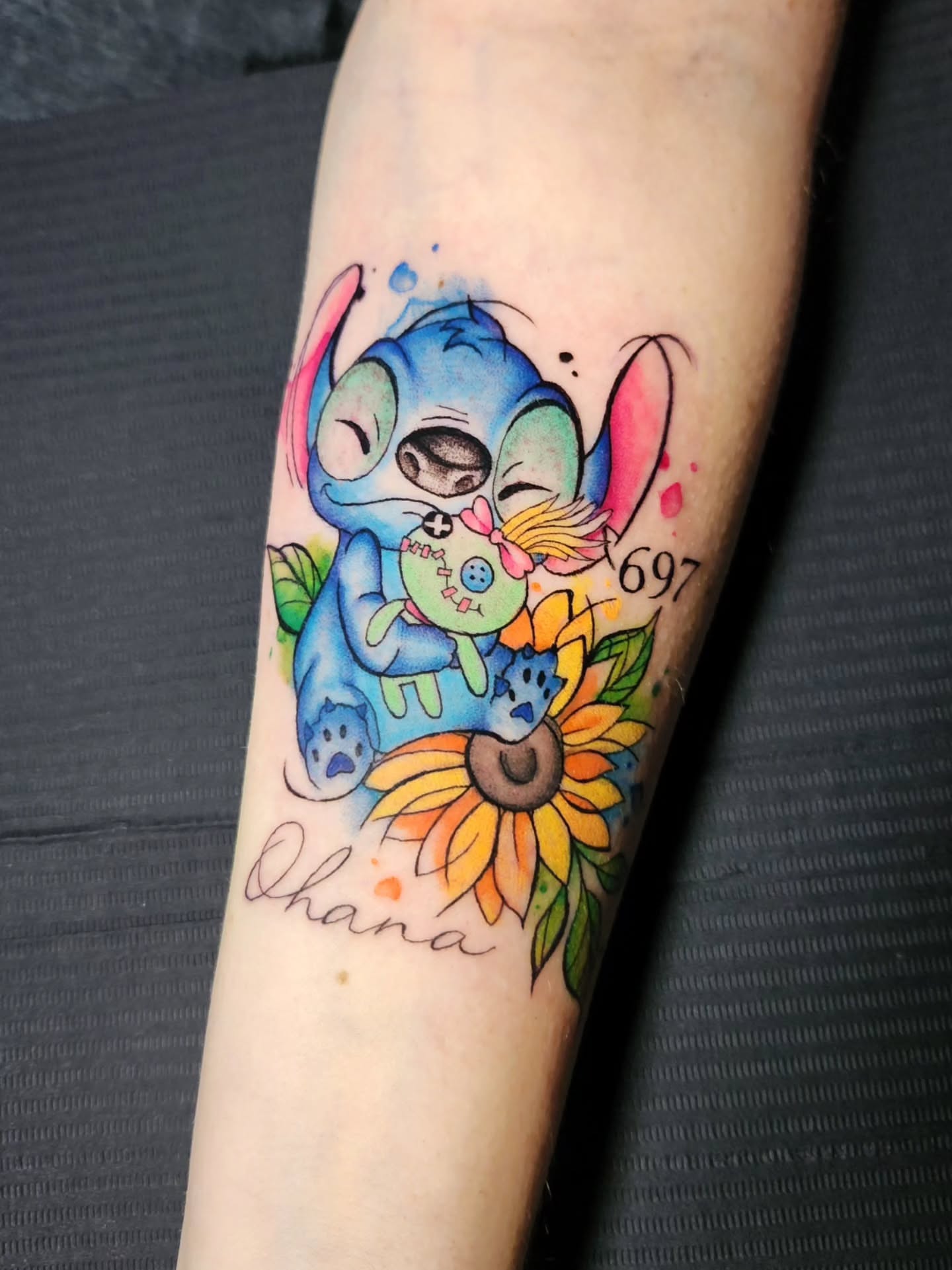 Stitch and sunflower watercolor tattoo on the forearm by Abby Renteria