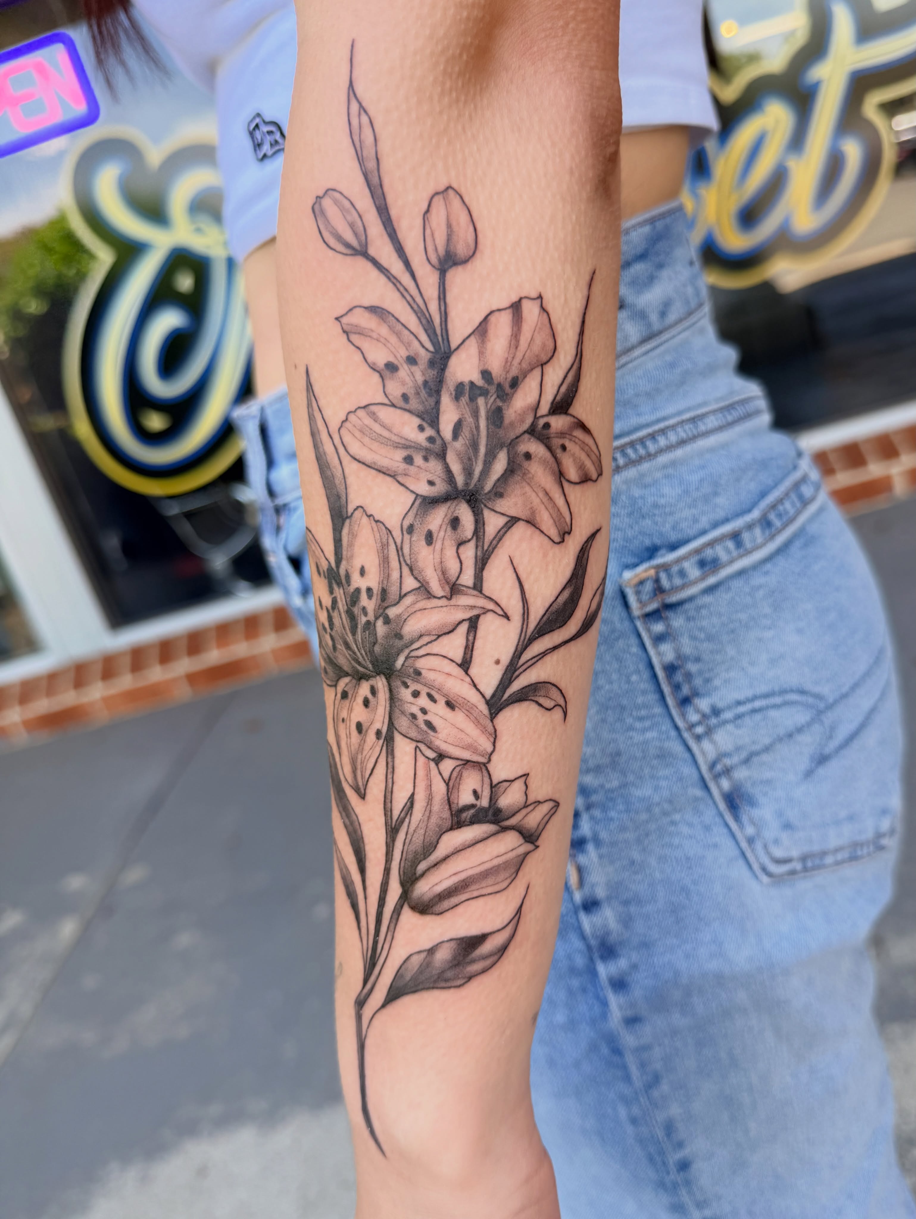 Lilies black and grey tattoo on the forearm by Maggie George