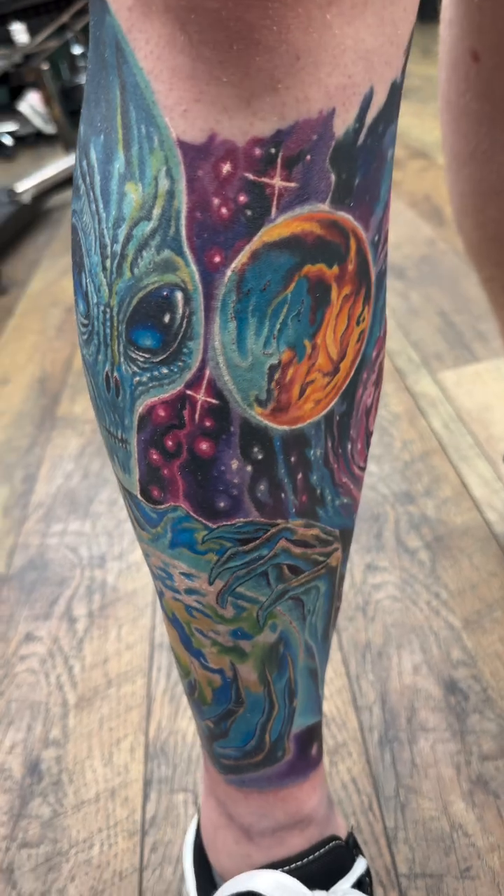 Alien and cosmic scene surrealism tattoo on the calf by Bryan Parsons