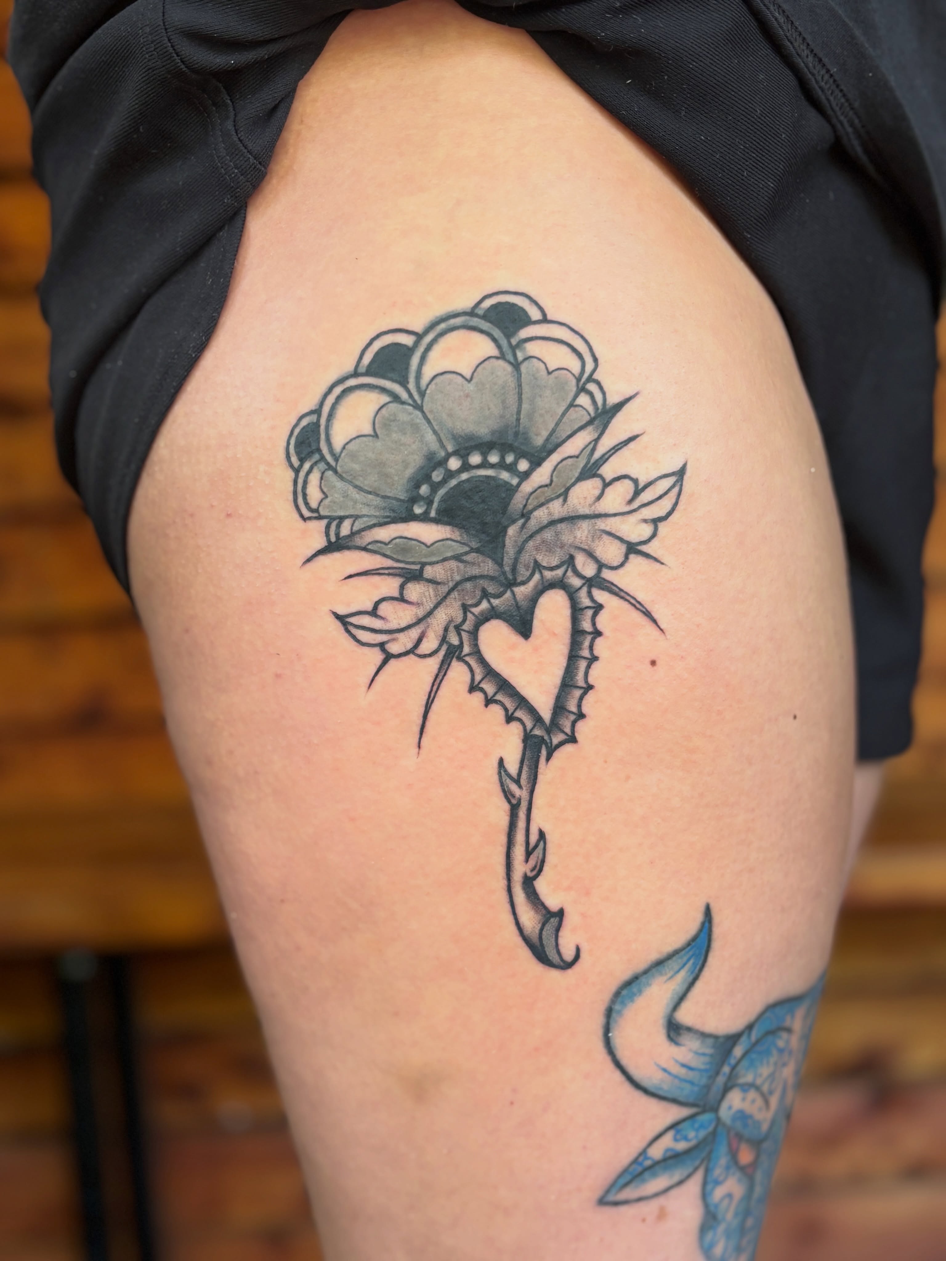 Flower with thorns black and grey tattoo on the thigh by Lilly Evans