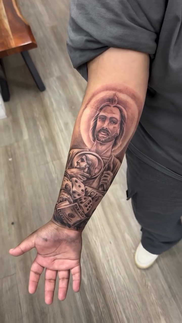 Jesus with dice and skulls realism tattoo on the forearm by Brian Cruz Garcia