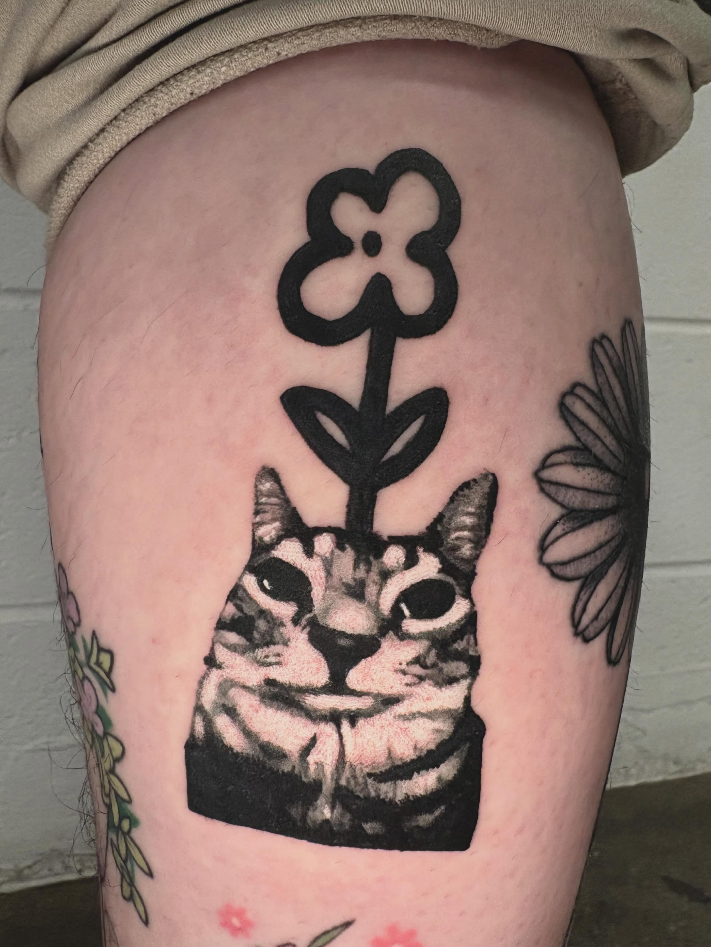 Cat with flower realism tattoo on the thigh by @lil_stinker_5000, Portland, Oregon