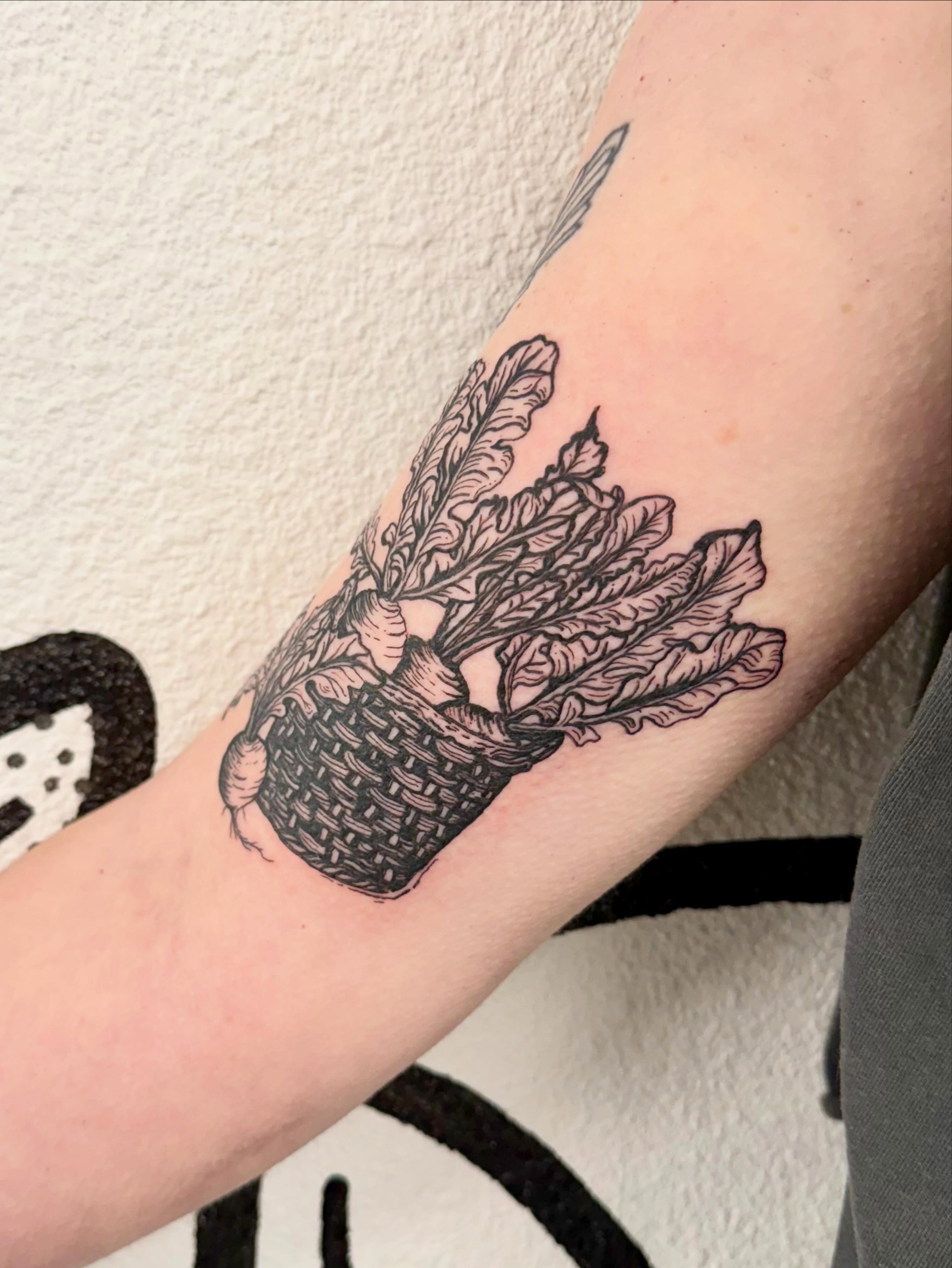Basket of leeks black and grey tattoo on the forearm by Peggy