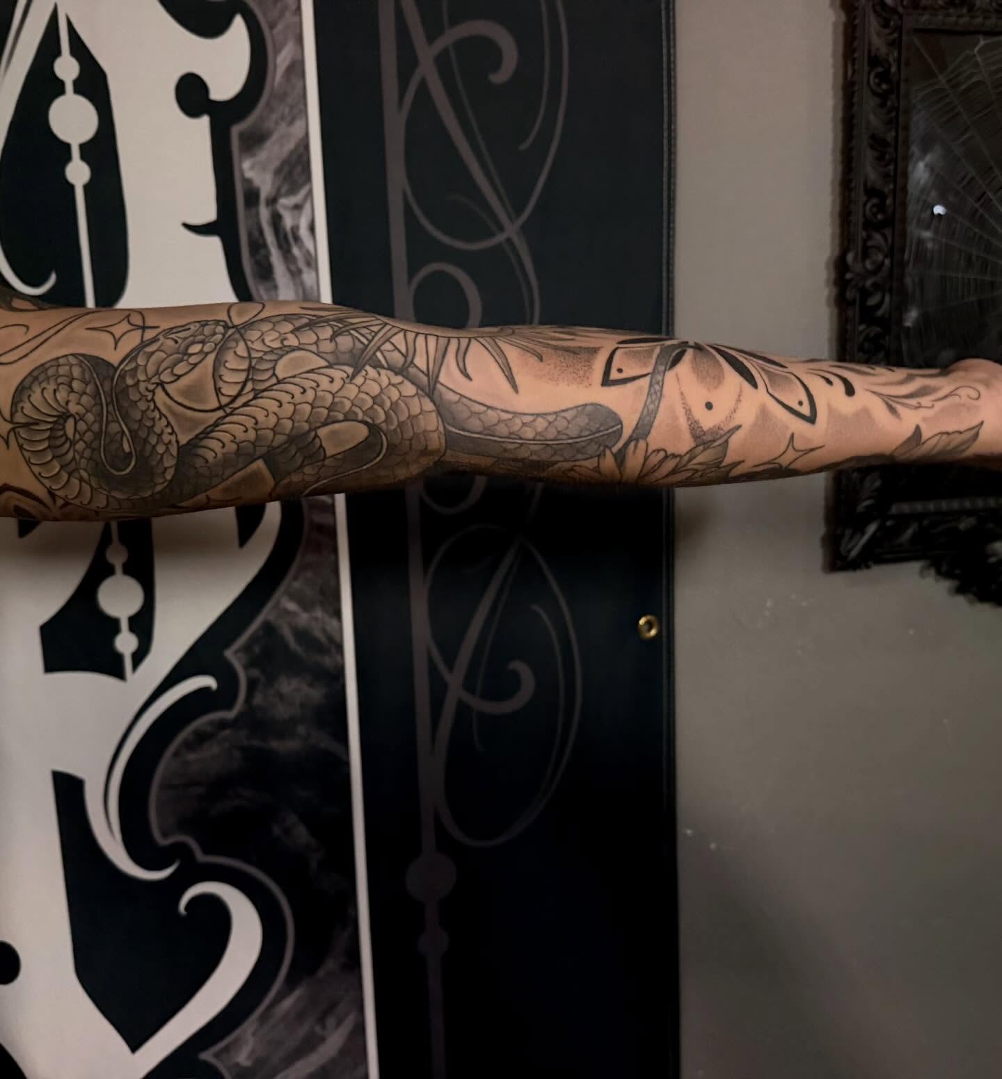 Snake and leaves black and grey tattoo on the forearm by Cody Pappas