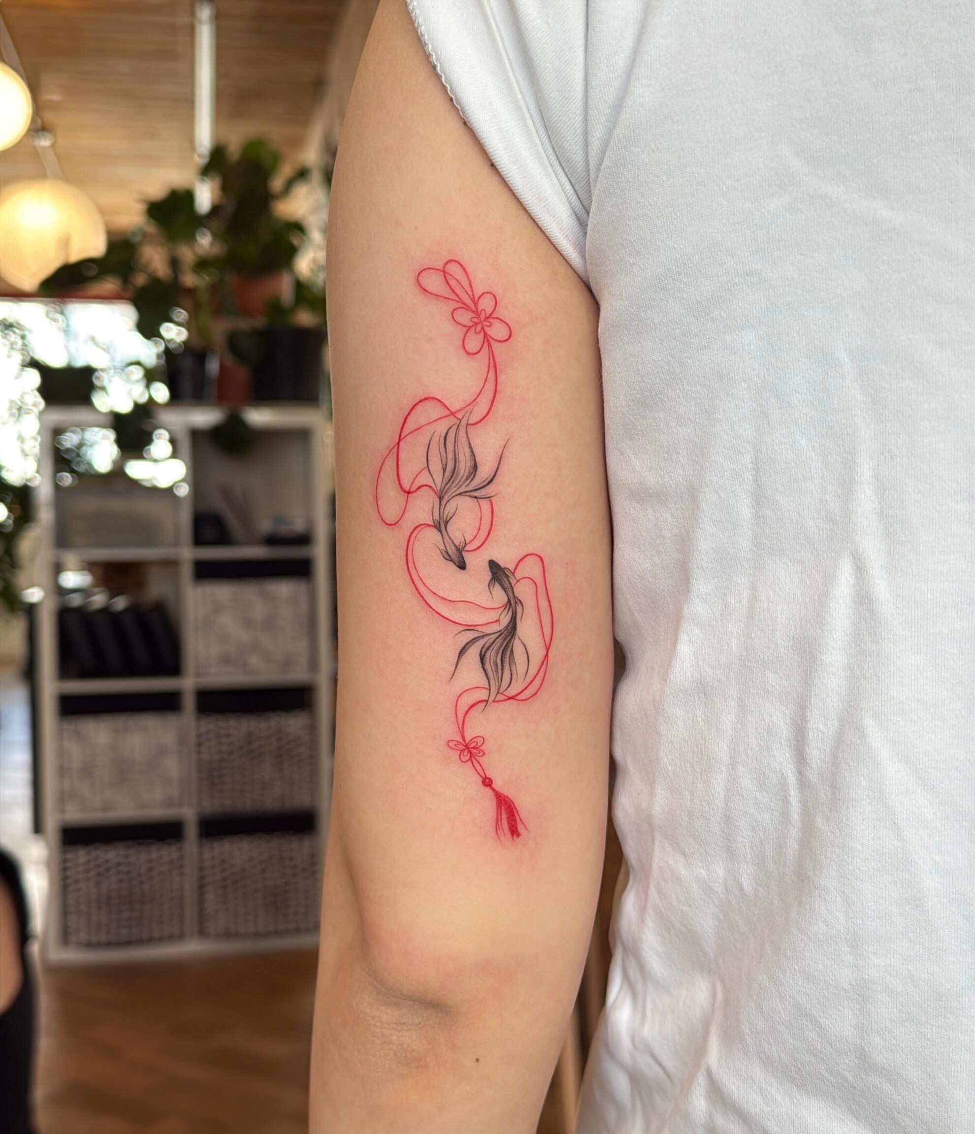 Koi fish and flower fine line tattoo on the forearm by Ethan