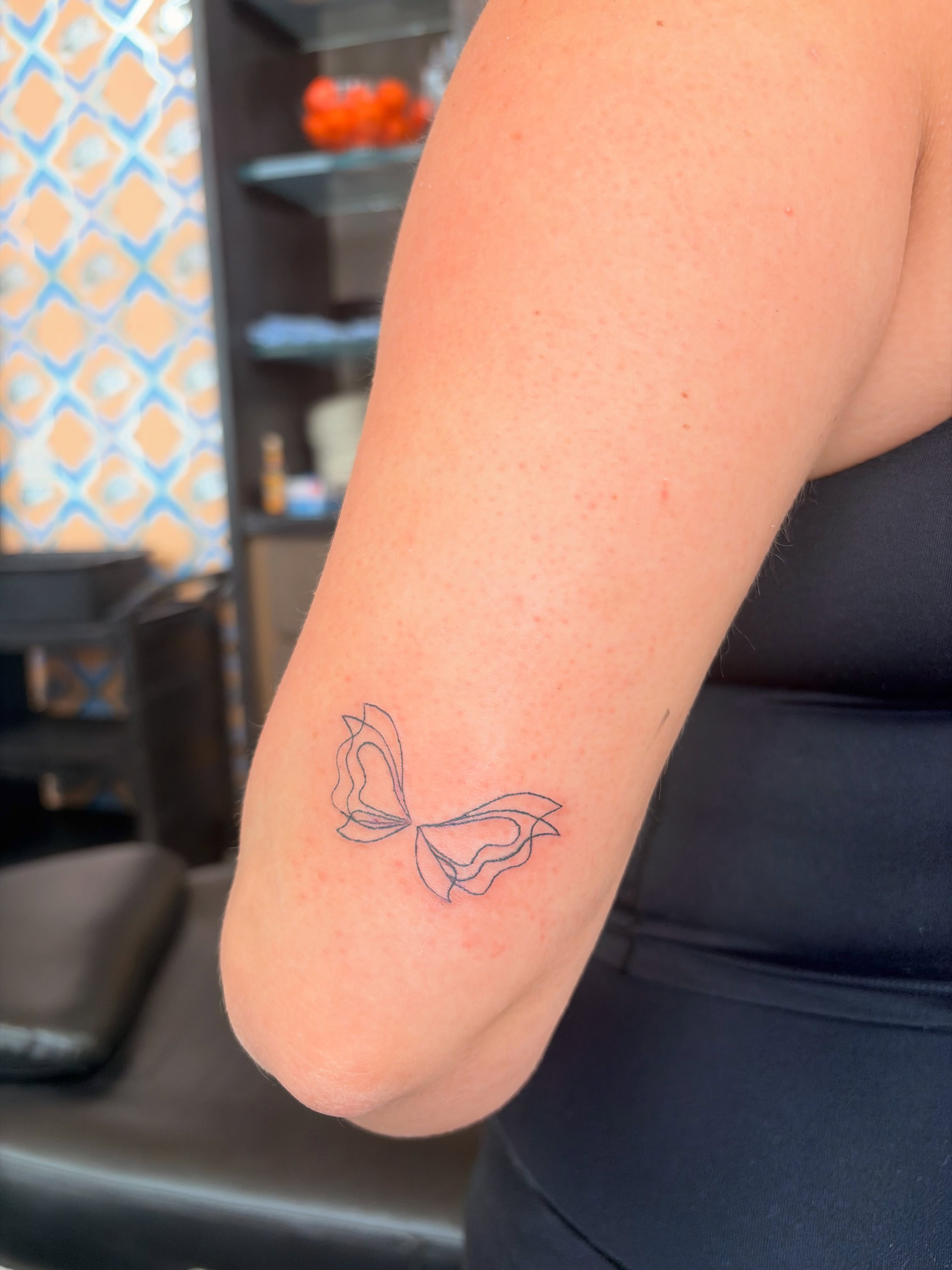 Bow fine line tattoo on the forearm by Inky Birdz Tattoos