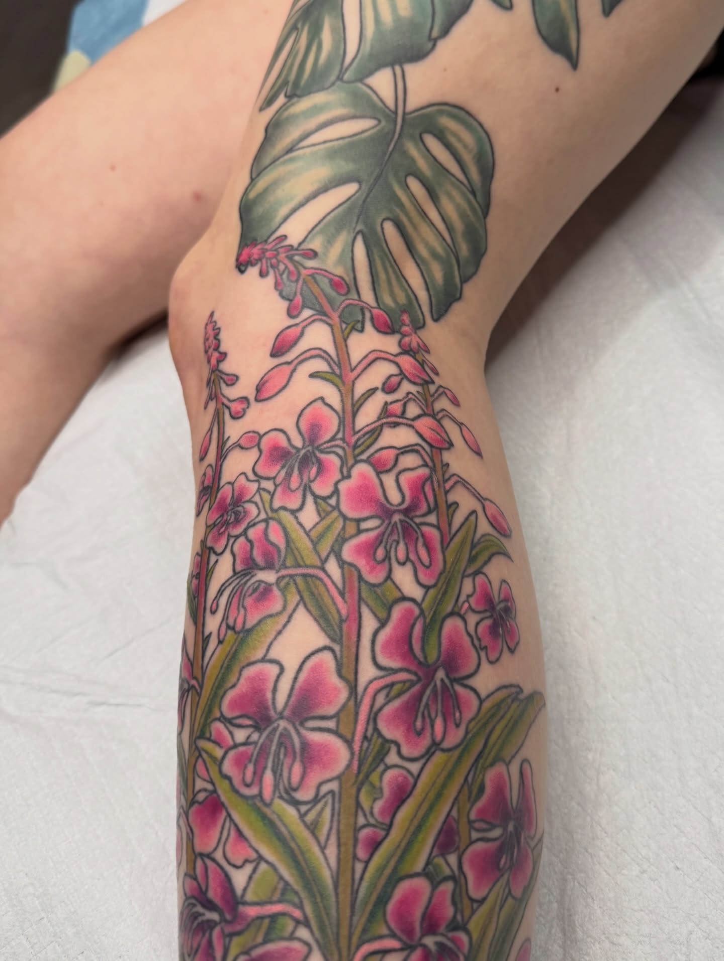 Orchids and monstera leaves new school tattoo on the forearm by Joel Smith, Manhattan, Kansas