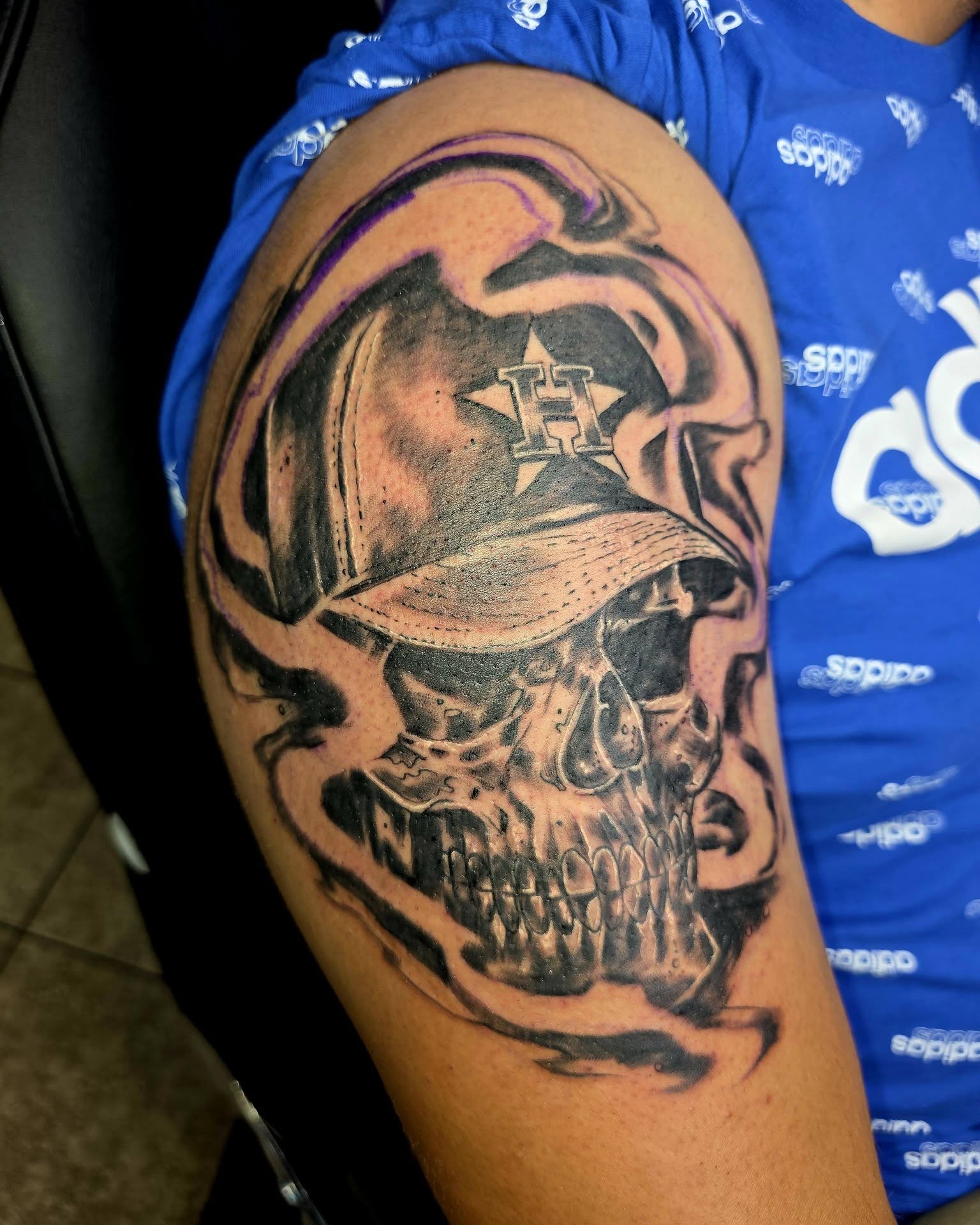 Skull wearing baseball cap realism tattoo on the shoulder by Jessica DarkRabbit