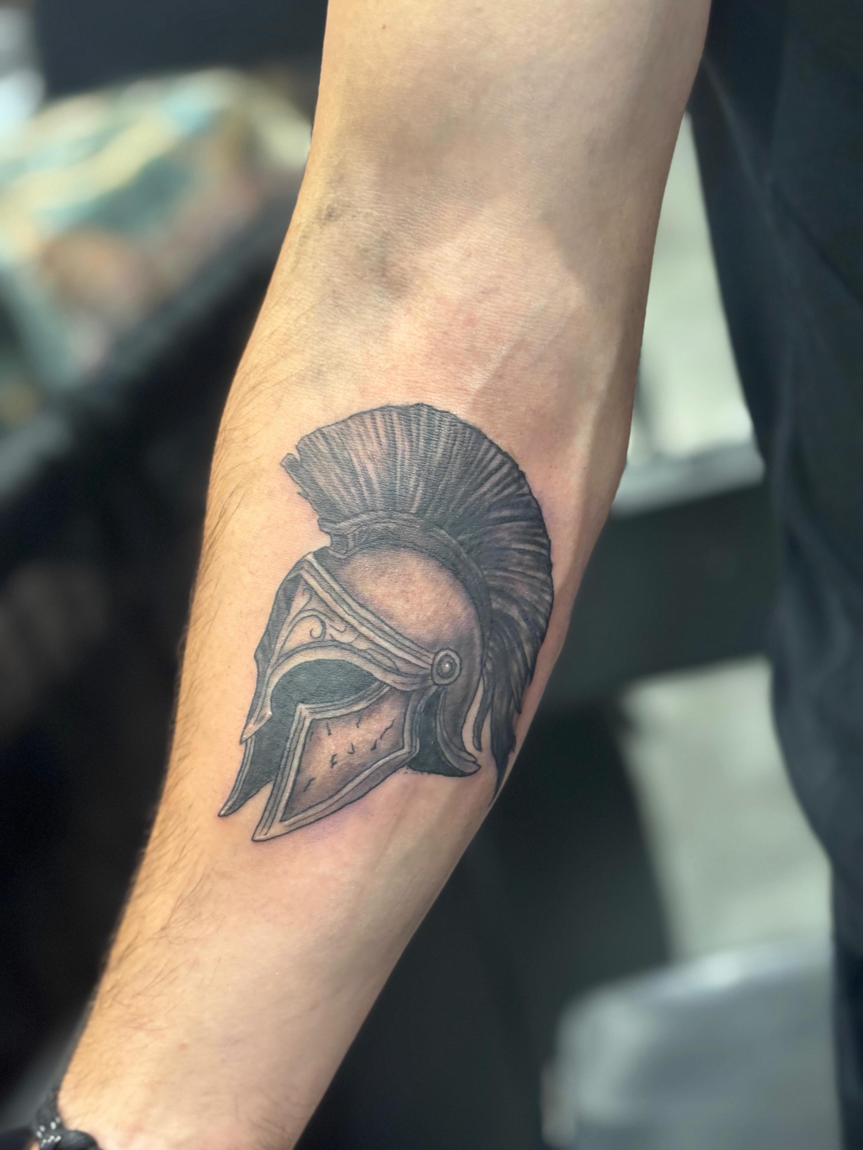 Spartan helmet black and grey tattoo on the forearm by Zeninkz