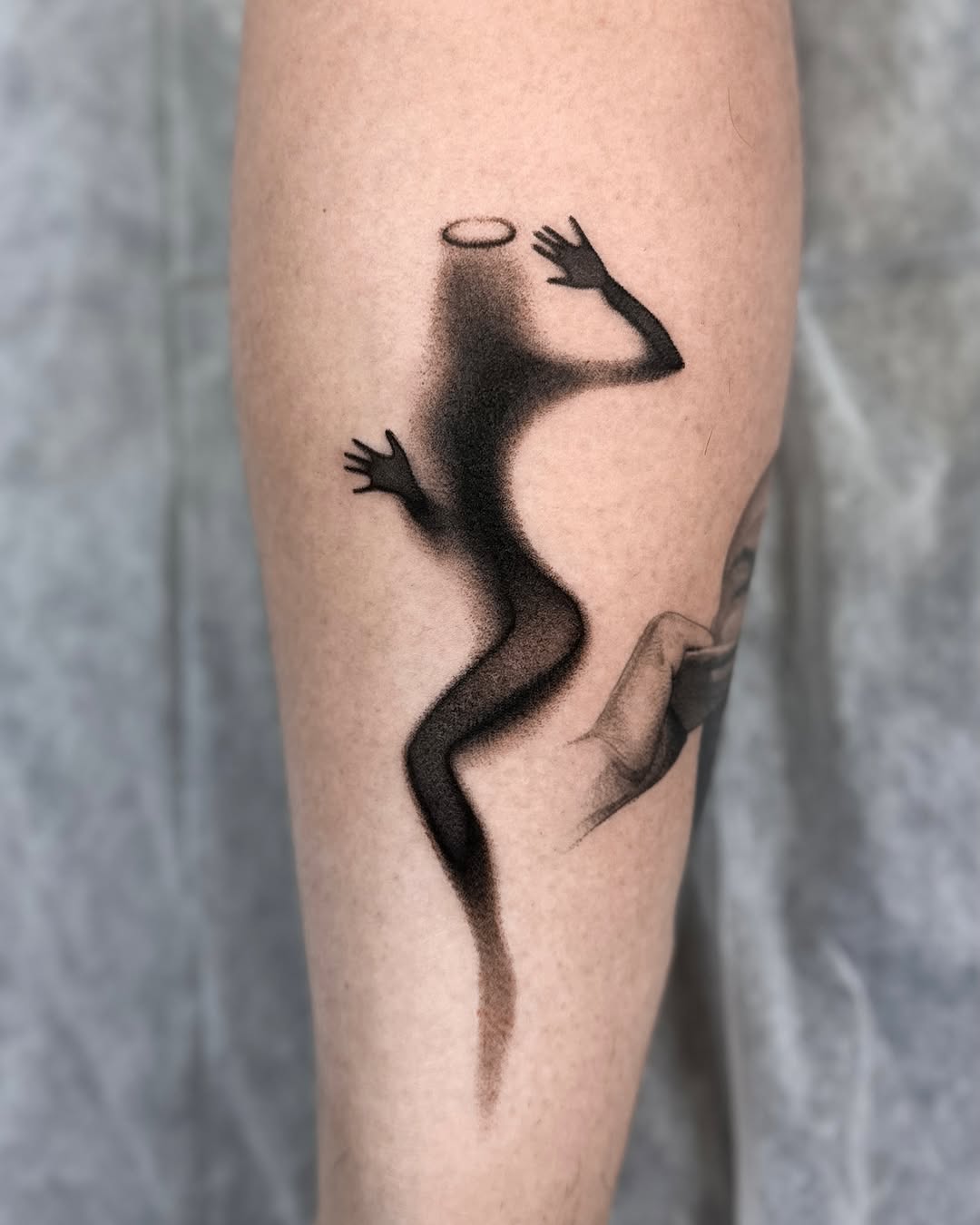 Shadow figure with halo surrealism tattoo on the forearm by Saru